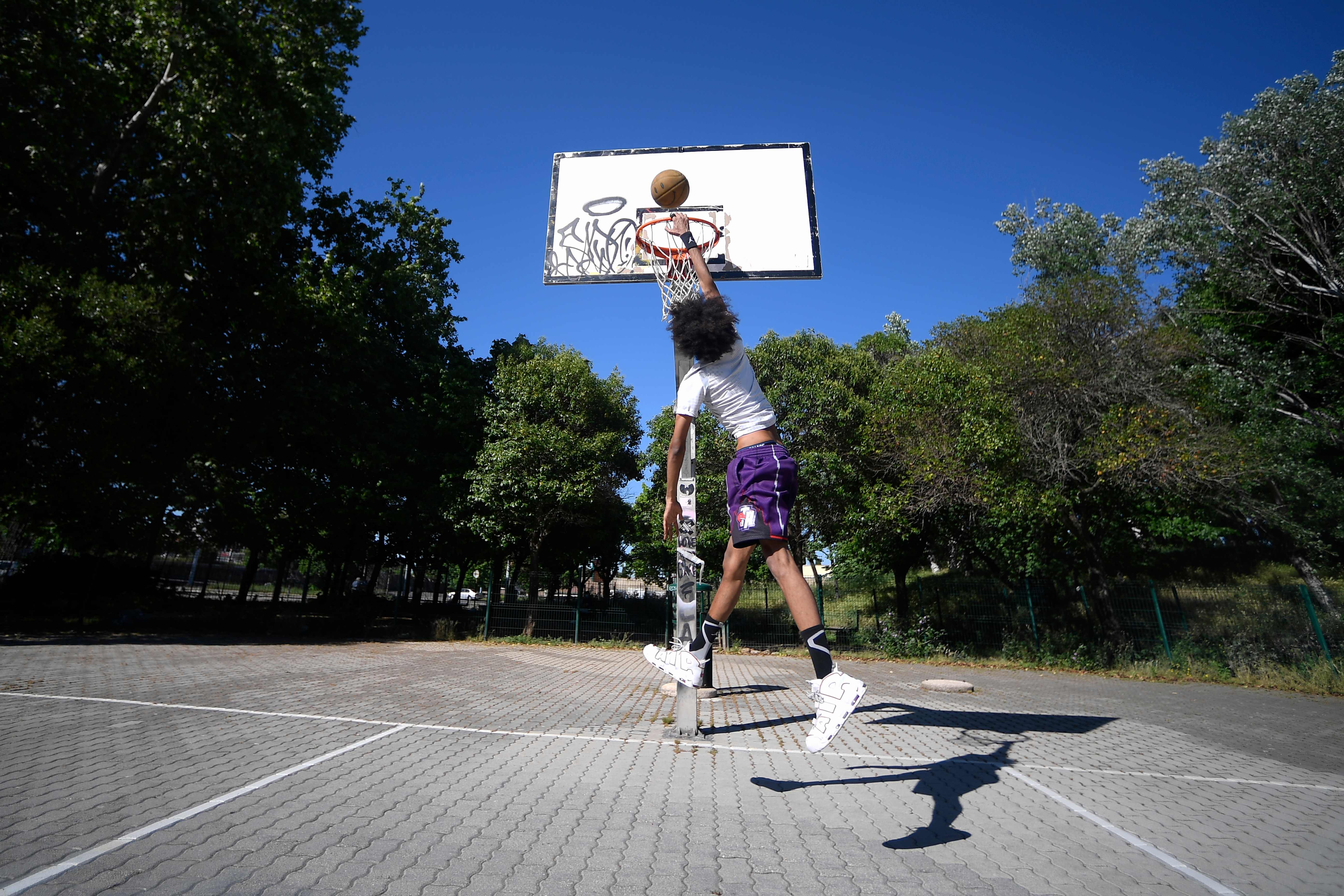 Seorang pemuda bermain basket di sebuah taman di Roma, Italia. Warga mulai beraktivitas setelah pemerintah Italia melonggarkan lockdown.
