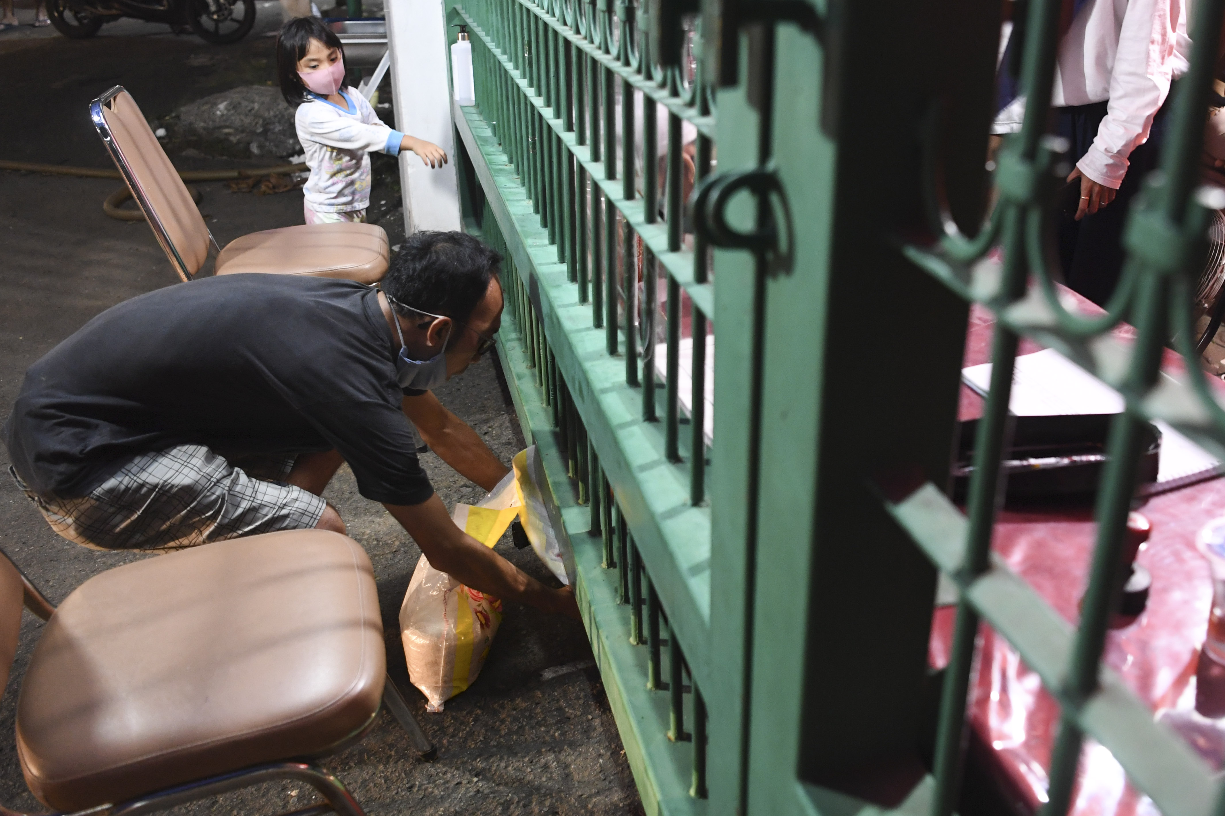 Seorang warga memasukkan beras di antara pagar saat membayar zakat fitrah di Jagakarsa, Jakarta, Jumat (22/5).