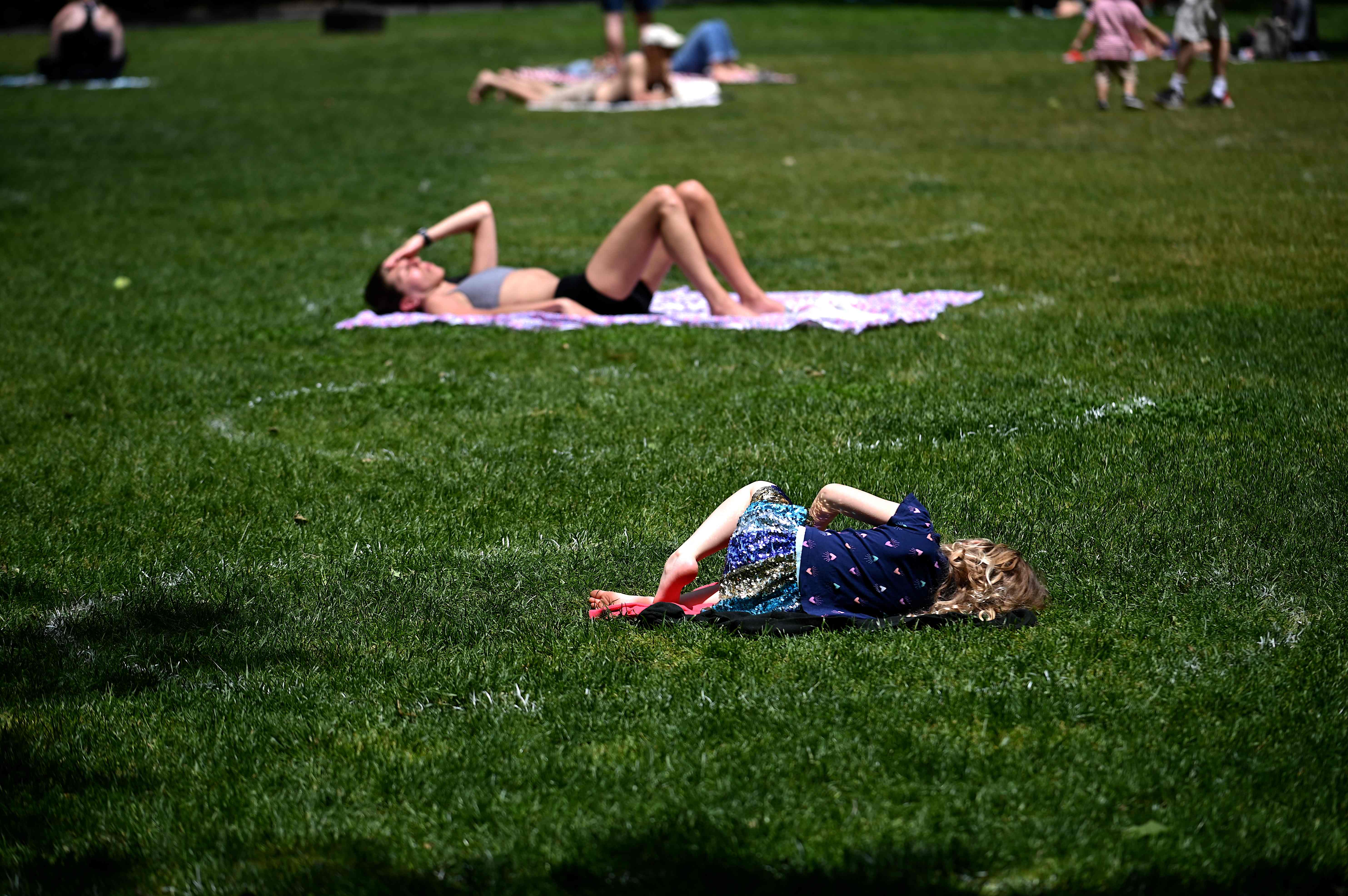 Warga menikmati hari yang cerah di Madison Square Park, New York, meski tetap menjaga jarak sosial dengan berada di lingkaran yang ada.