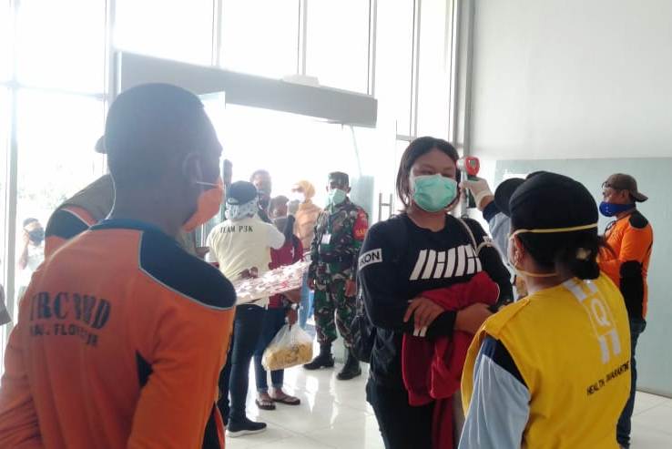 Petugas pelabuhan mengecek suhu tubuh penumpang.