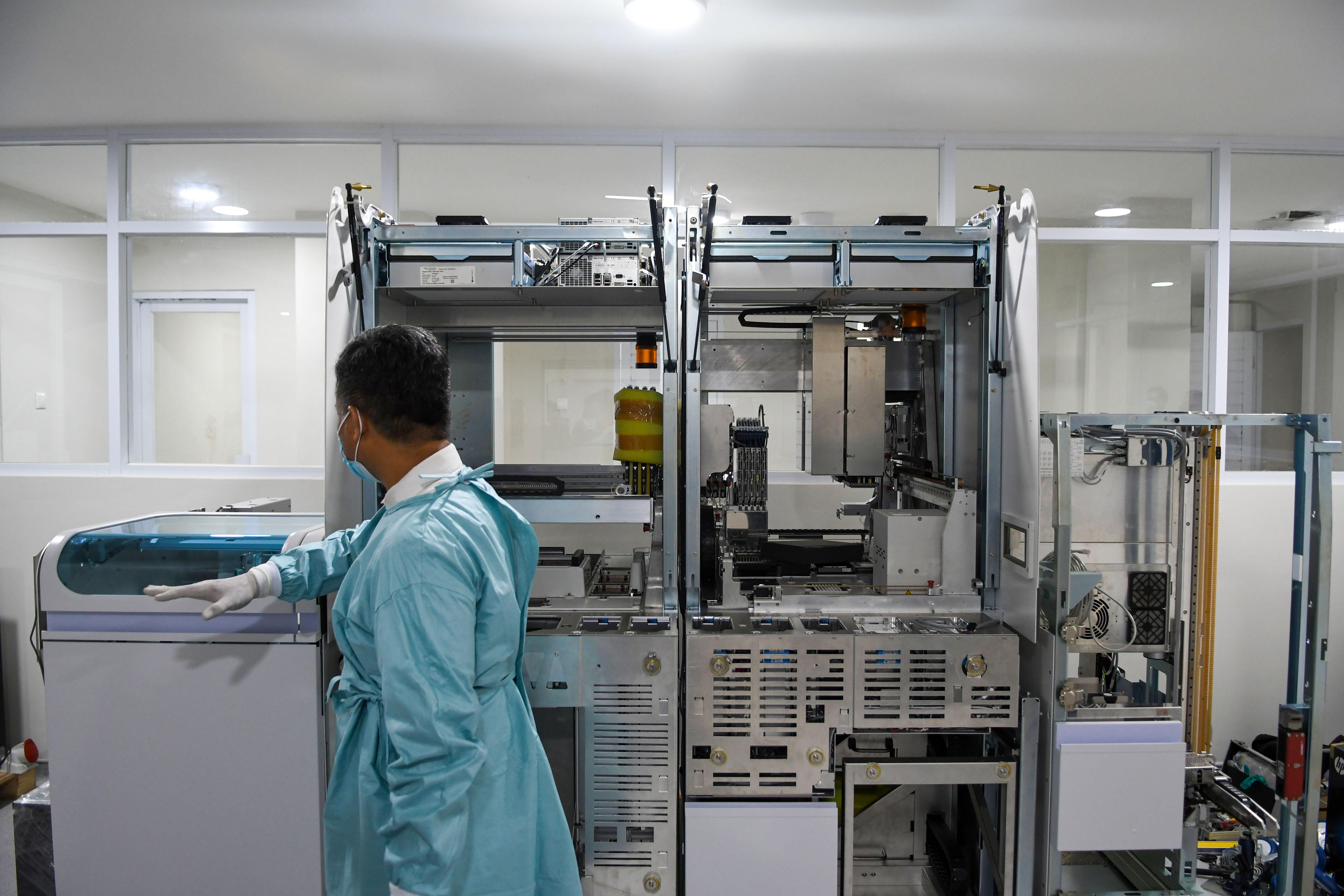 Seorang dokter di dekat alat Polymerase Chain Reaction (PCR).