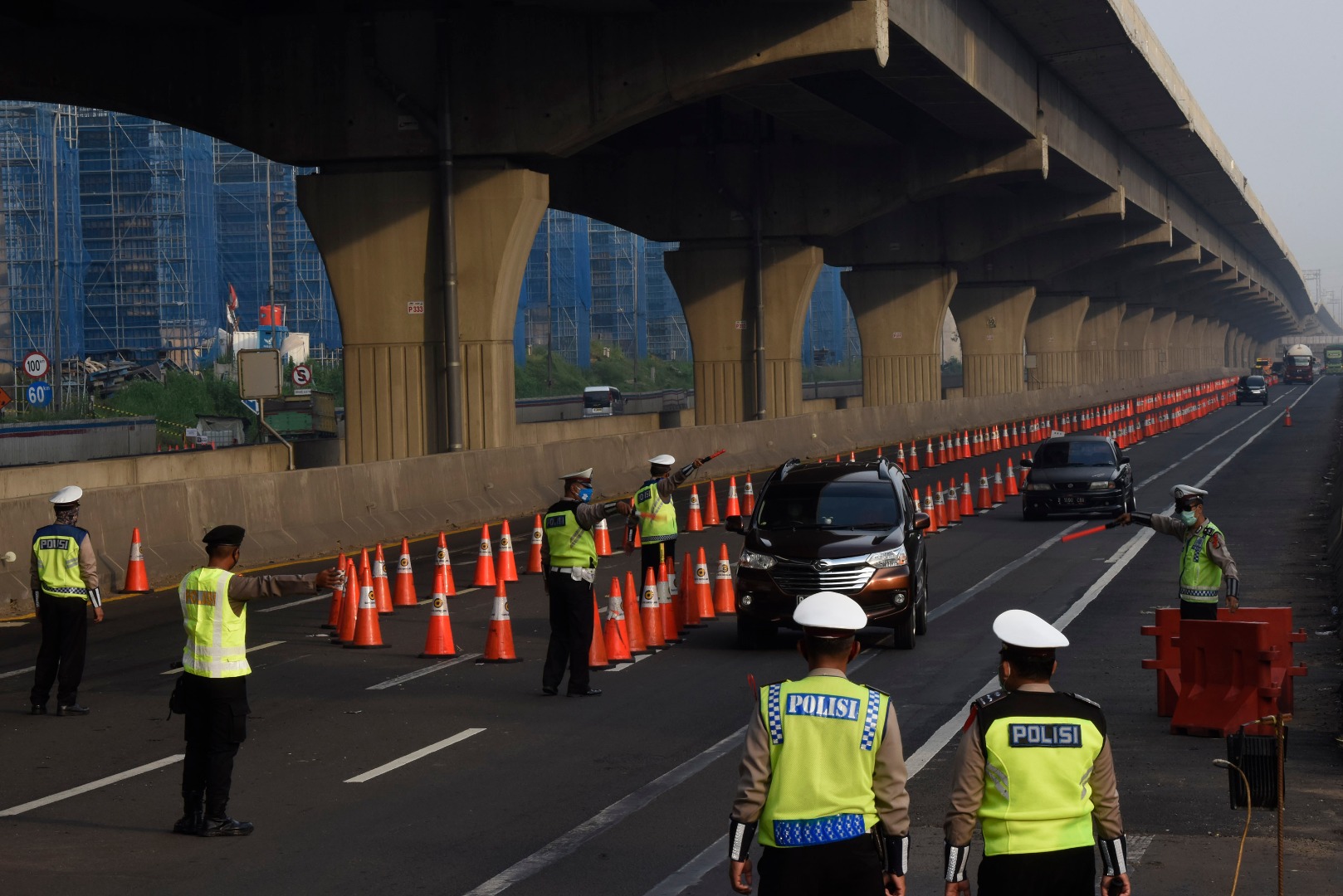 Petugas gabungan mengarahkan kendaraan untuk keluar Tol Cikarang Barat, di ruas Tol Cikampek, Jabar.