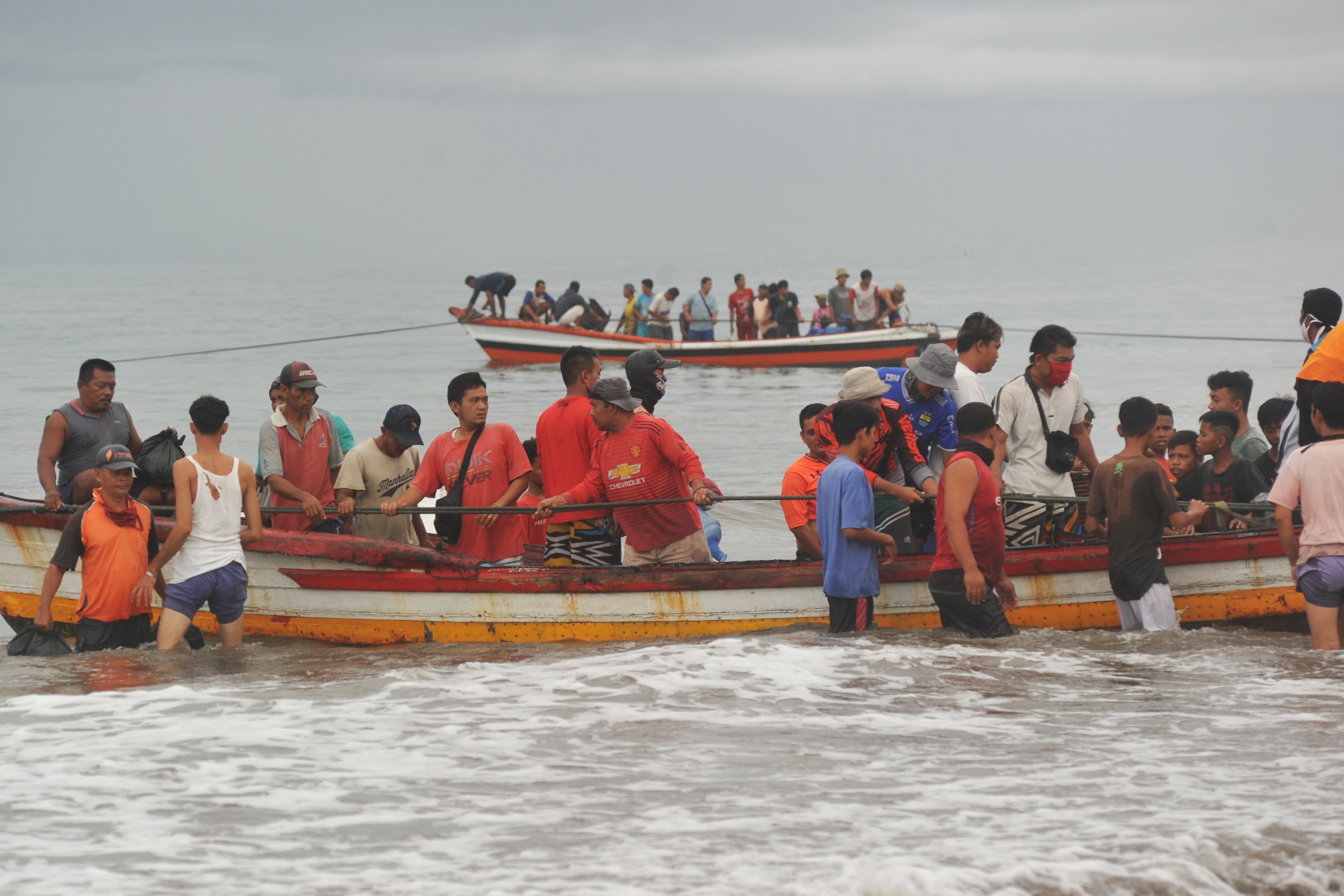 Nelayan dan anak-anak menurunkan hasil melaut di Pantai Pasie Nan Tigo, Padang, Sumatra Barat, Kamis (30/4). 
