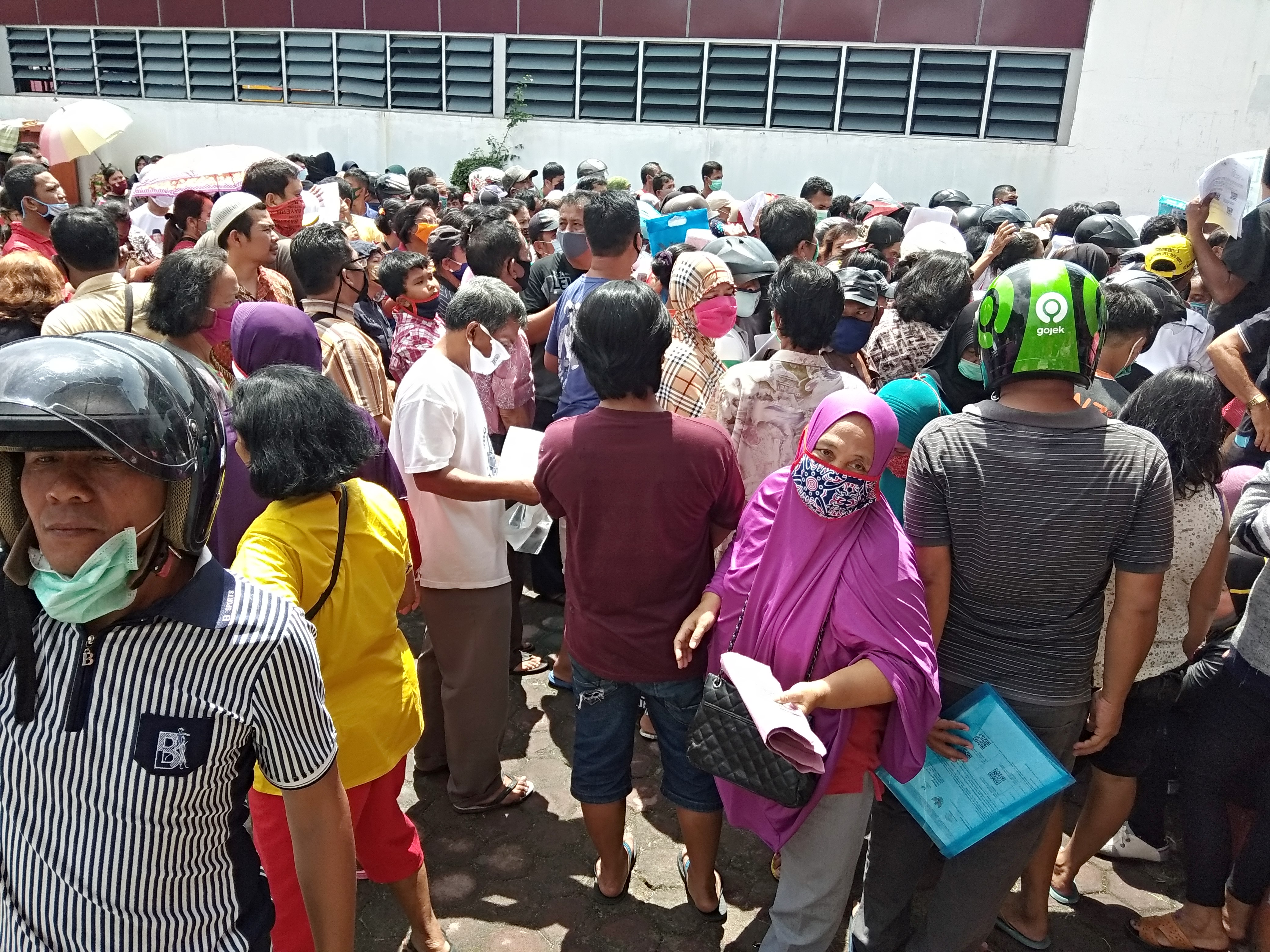 Warga berkerumun dan banyak tidak memakai masker saat antri mendapatkan bantuan sosial tunai di Kantor Pos Pematangsiantar, Rabu (13/5/2020)