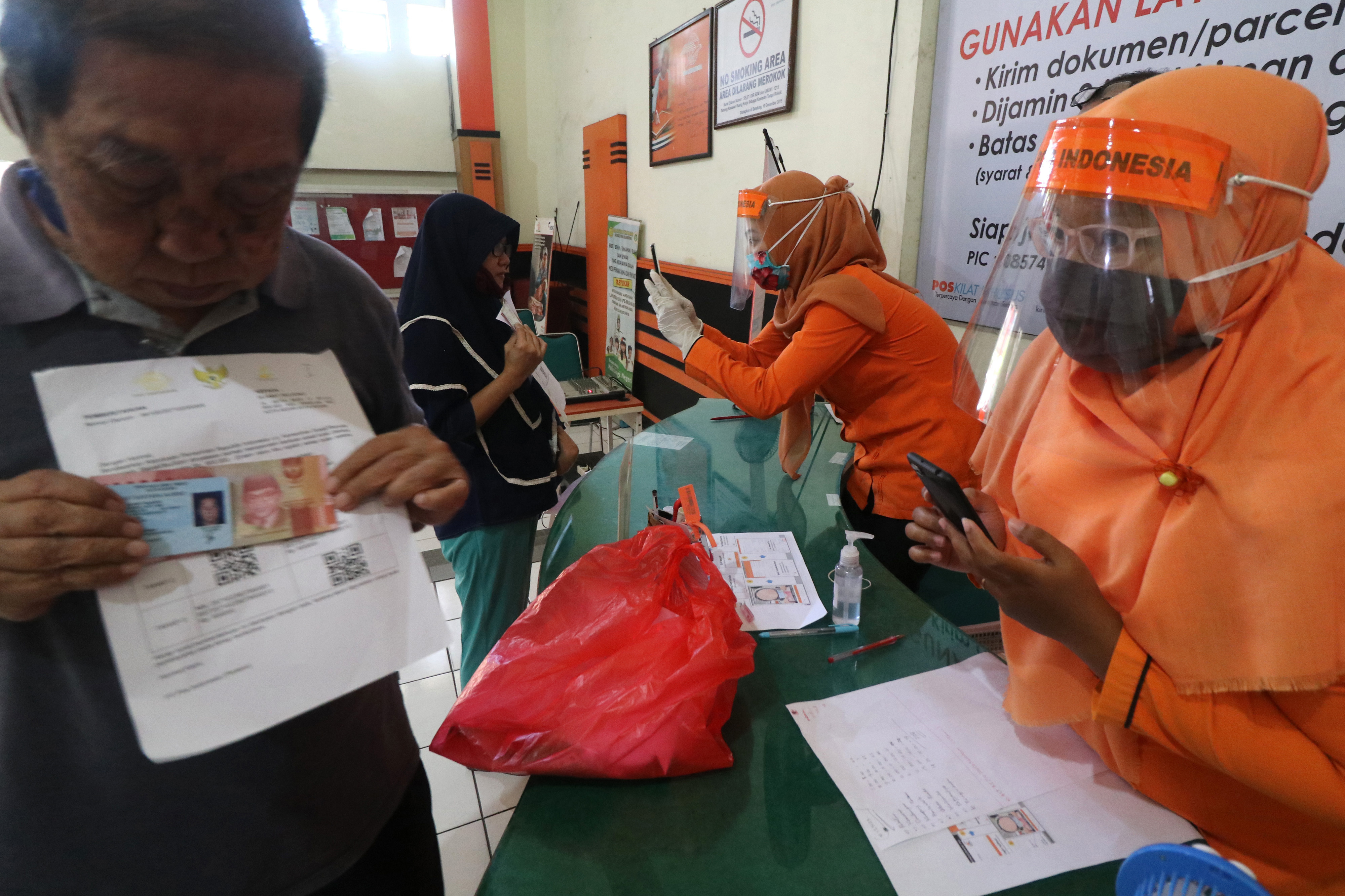 Petugas memotret warga penerima bantuan sebaga tanda bukti pencairan Bantuan Sosial Tunai di Kantor Pos Besar, Kota Kediri