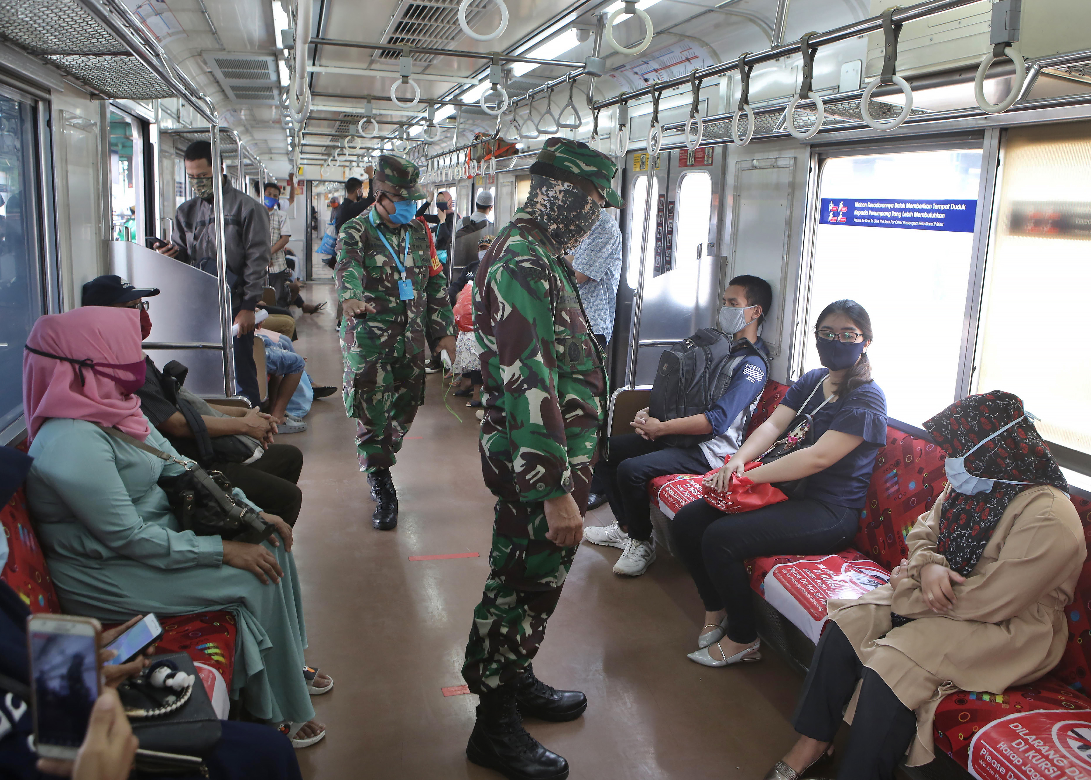 Anggota TNI memberikan imbauan pendisiplinan protokol kesehatan pencegahan covid-19 kepada para penumpang KRL di Stasiun Manggarai.