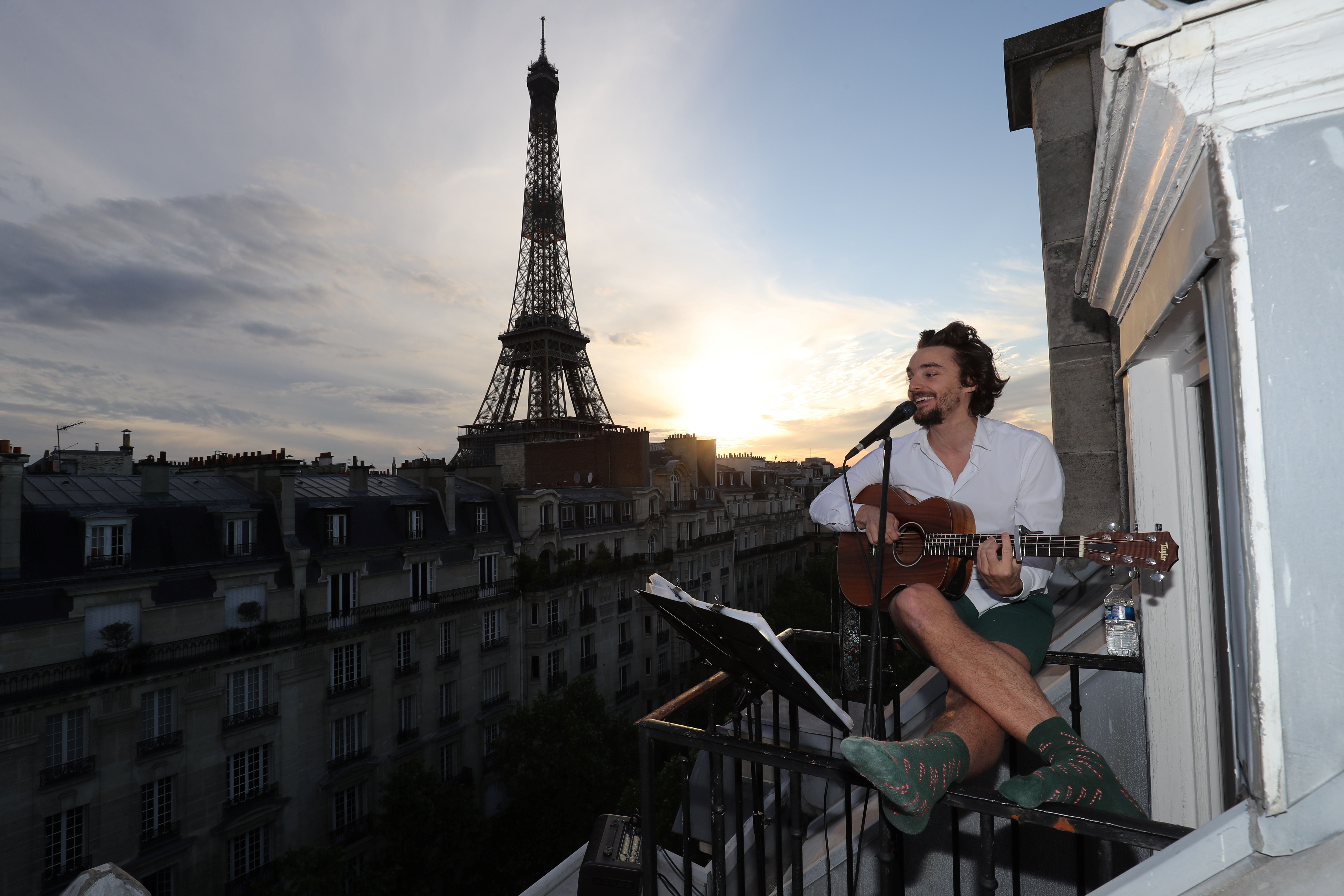 Penyanyi Andrien Pelon menyanyikan lagu di depan balkon apartemennya di Paris. Negara tersebut masih dikunci untuk menghentikan covid