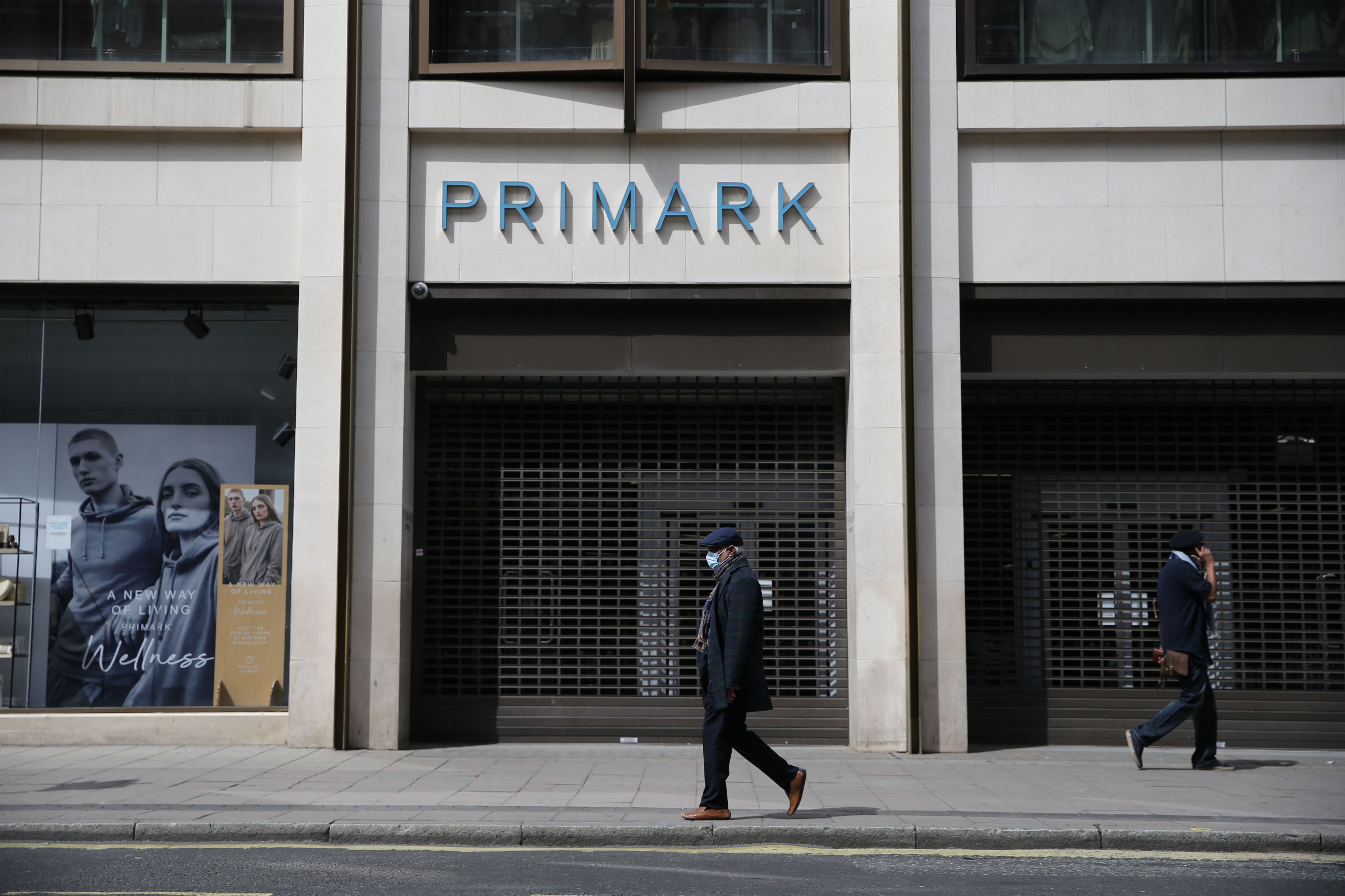 Warga melintas di depan pusat perbelanjaan Primark yang tutup di London, Inggris.