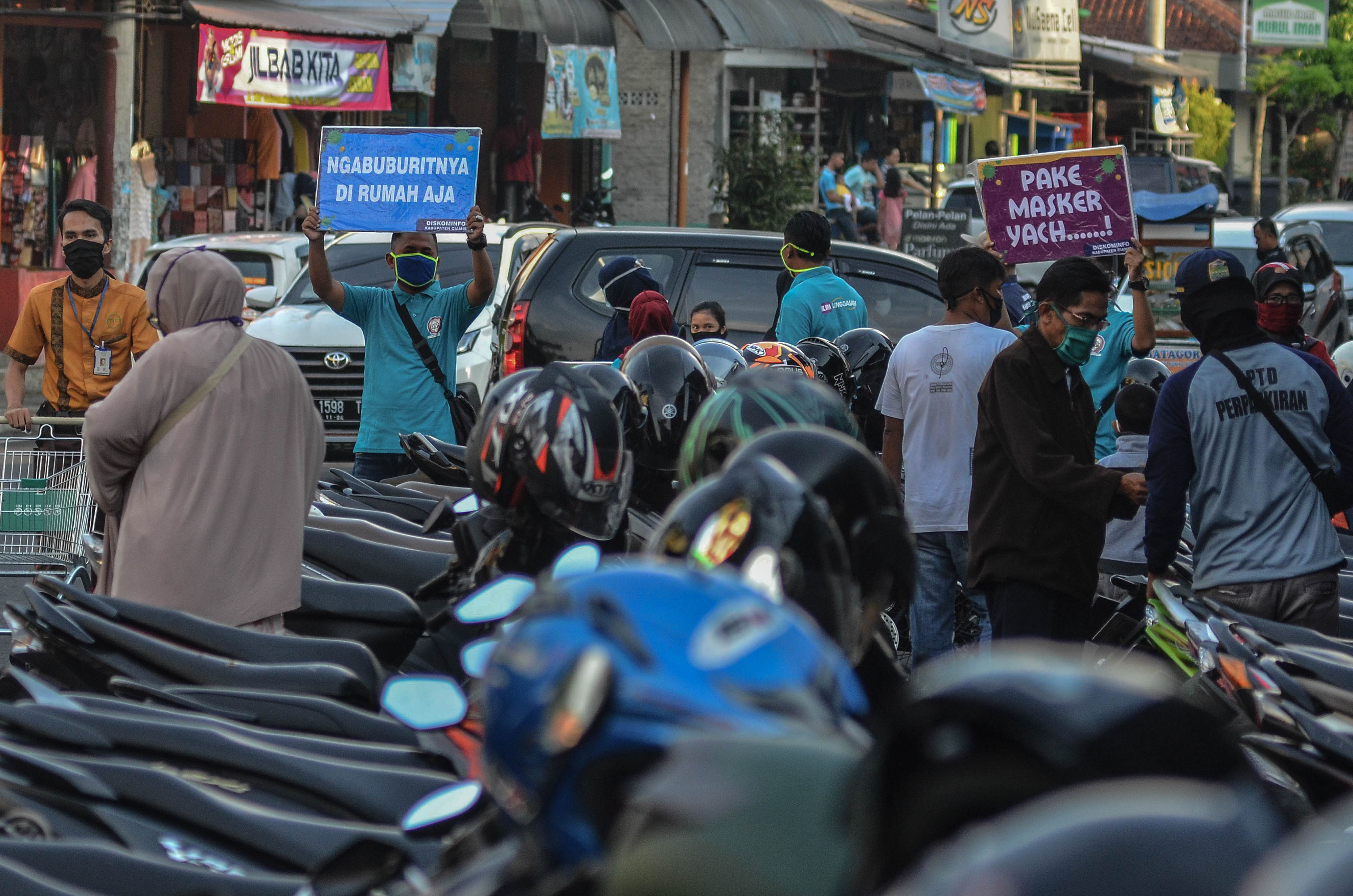  Relawan Covid-19 membawa poster bertuliskan imbauan saat berpatroli keliling pusat keramaian di Kabupaten Ciamis, Jawa Barat, Jumat (15/5)