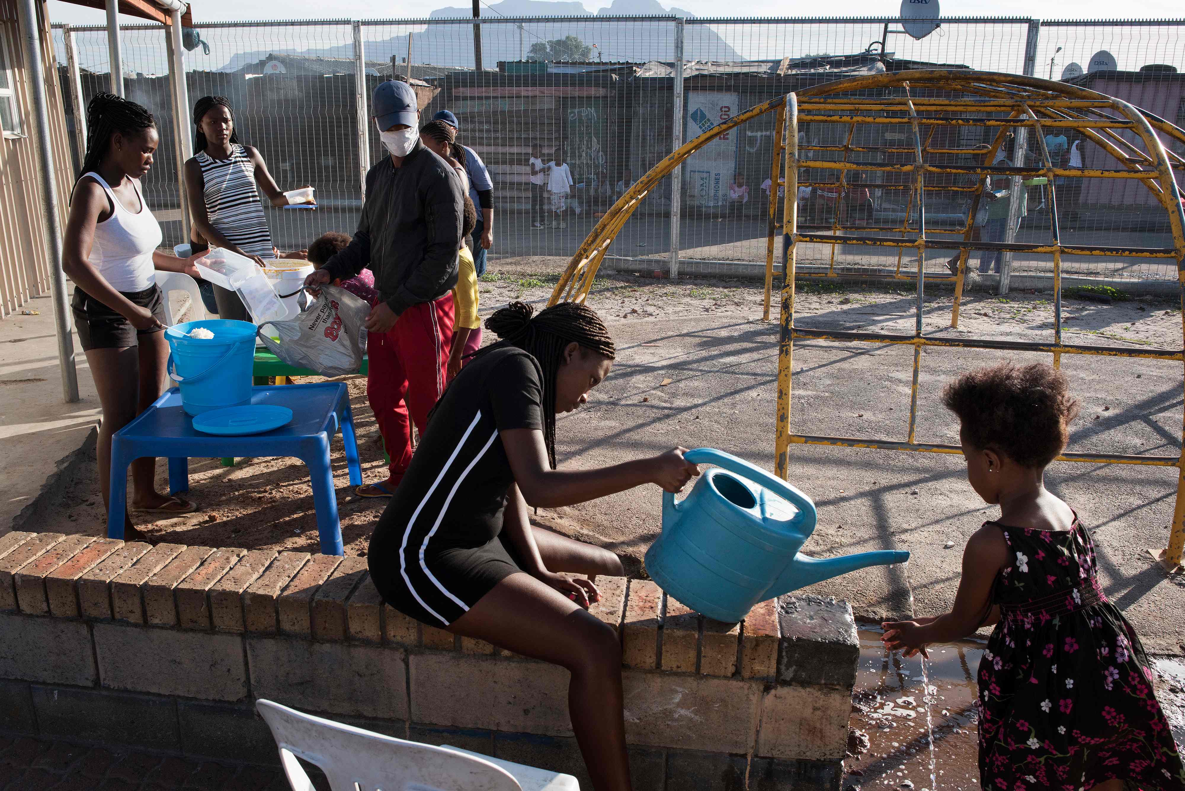 Anak-anak mencuci tangan sebelum mendapatkan paket makanan bagi warga yang terdampak covid-19 di Johannesburg, Afsel.