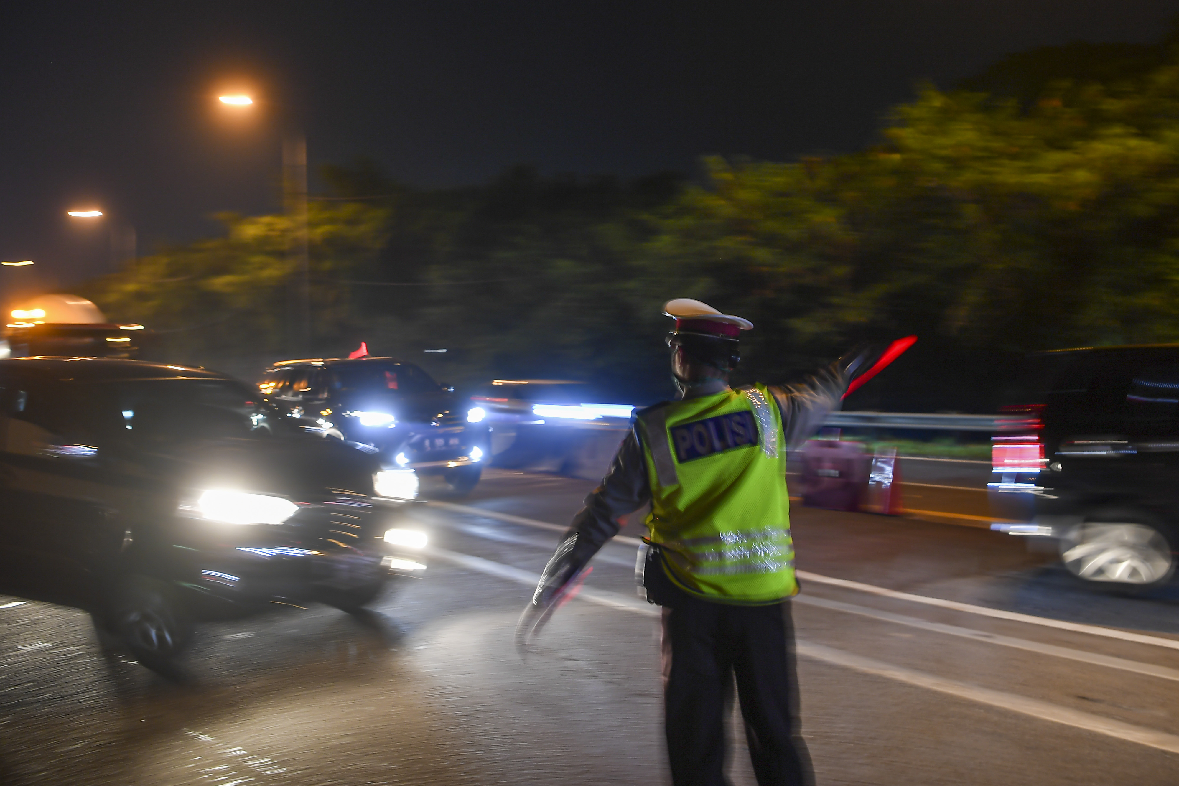 Petugas kepolisian mengarahkan kendaraan pribadi yang melintas di tol Jakarta-Cikampek untuk keluar.