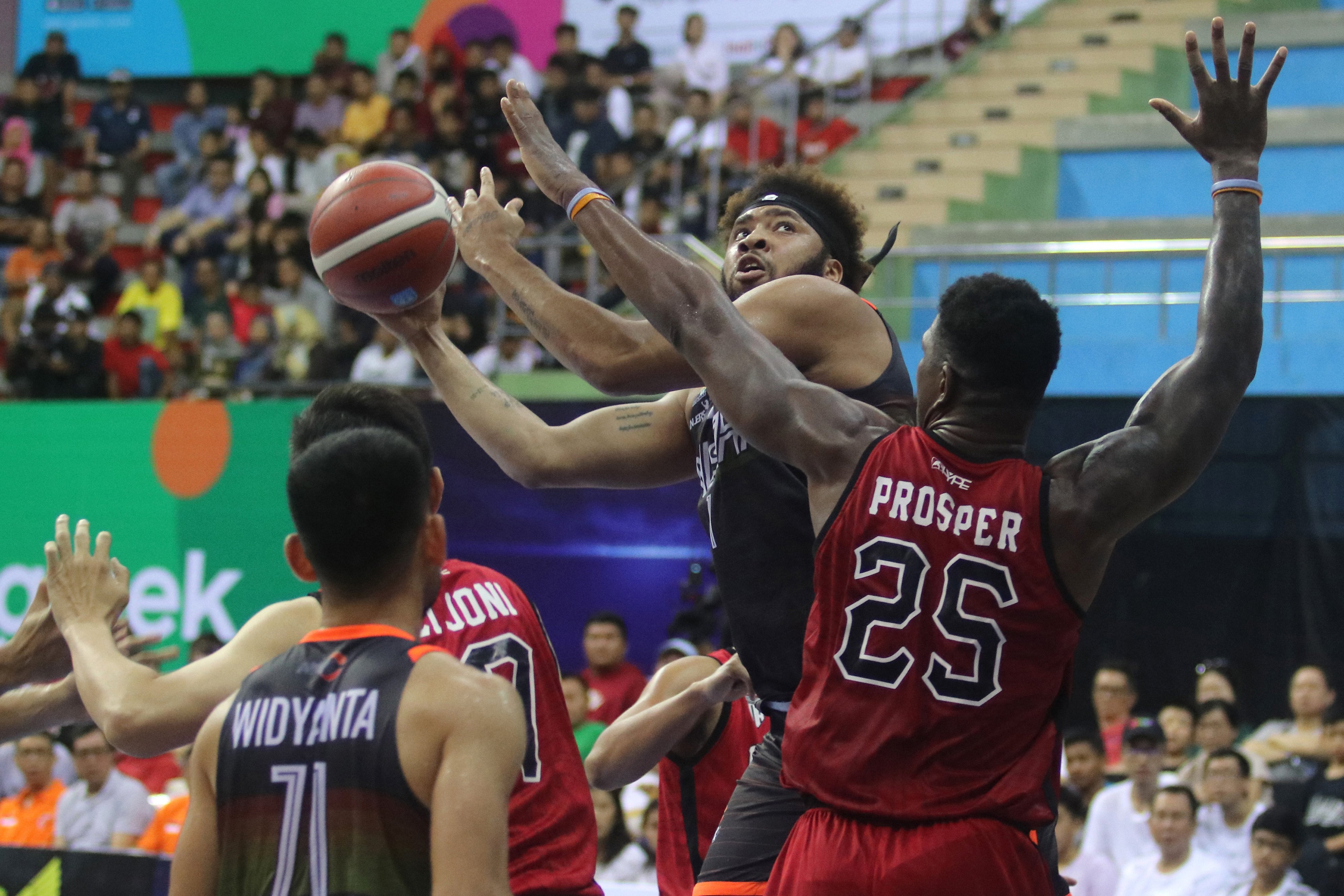 Pemain NSH Jakarta Michael Edward Glover (kedua kanan) berusaha memasukkan bola ke basket dihalangi tim basket Indonesia Patriots