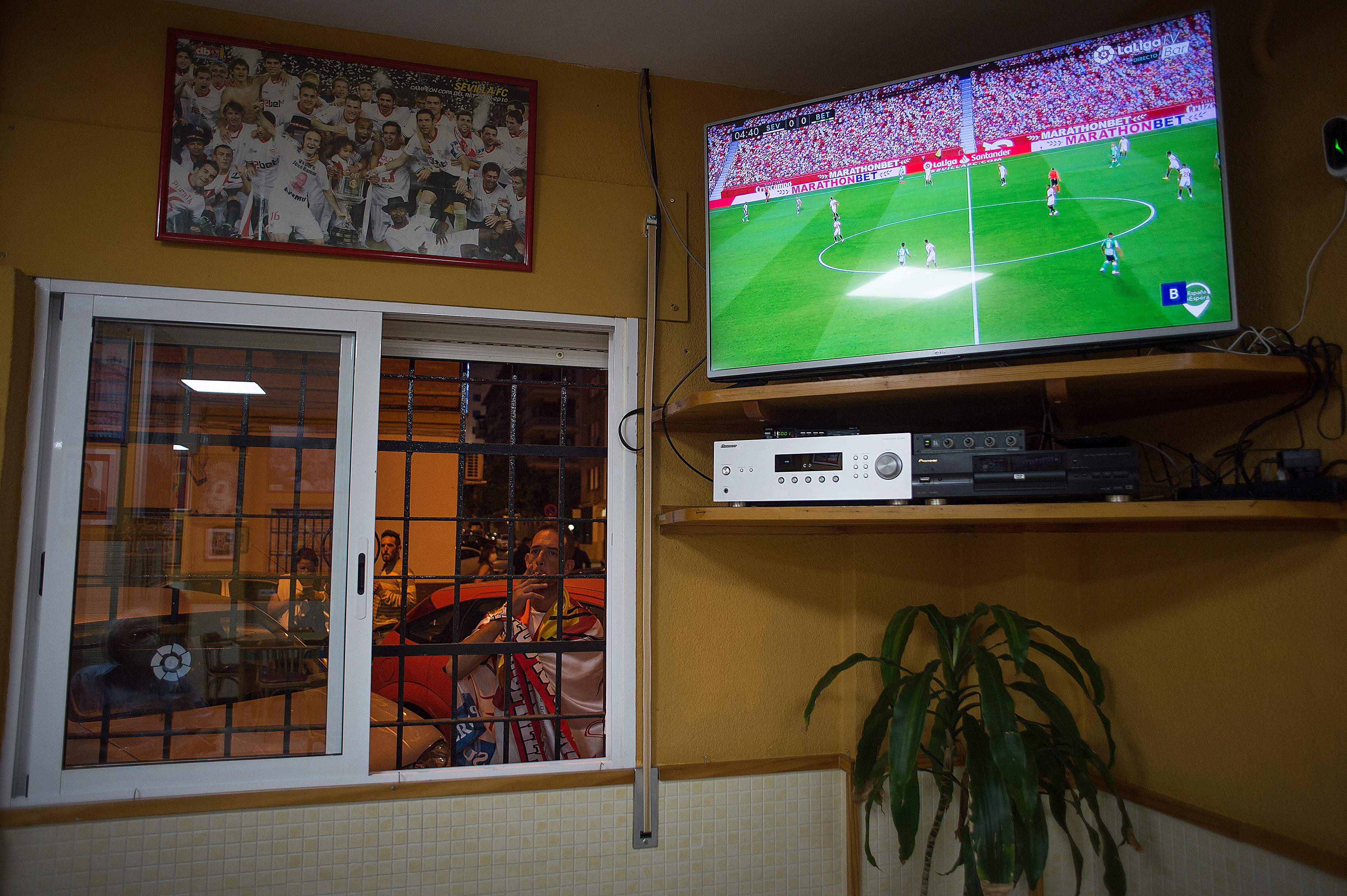 Penonton menyaksikan siaran langsung pertandingan sepak bola Liga Spanyol antara Sevilla FC dan Real Betis di televisi 