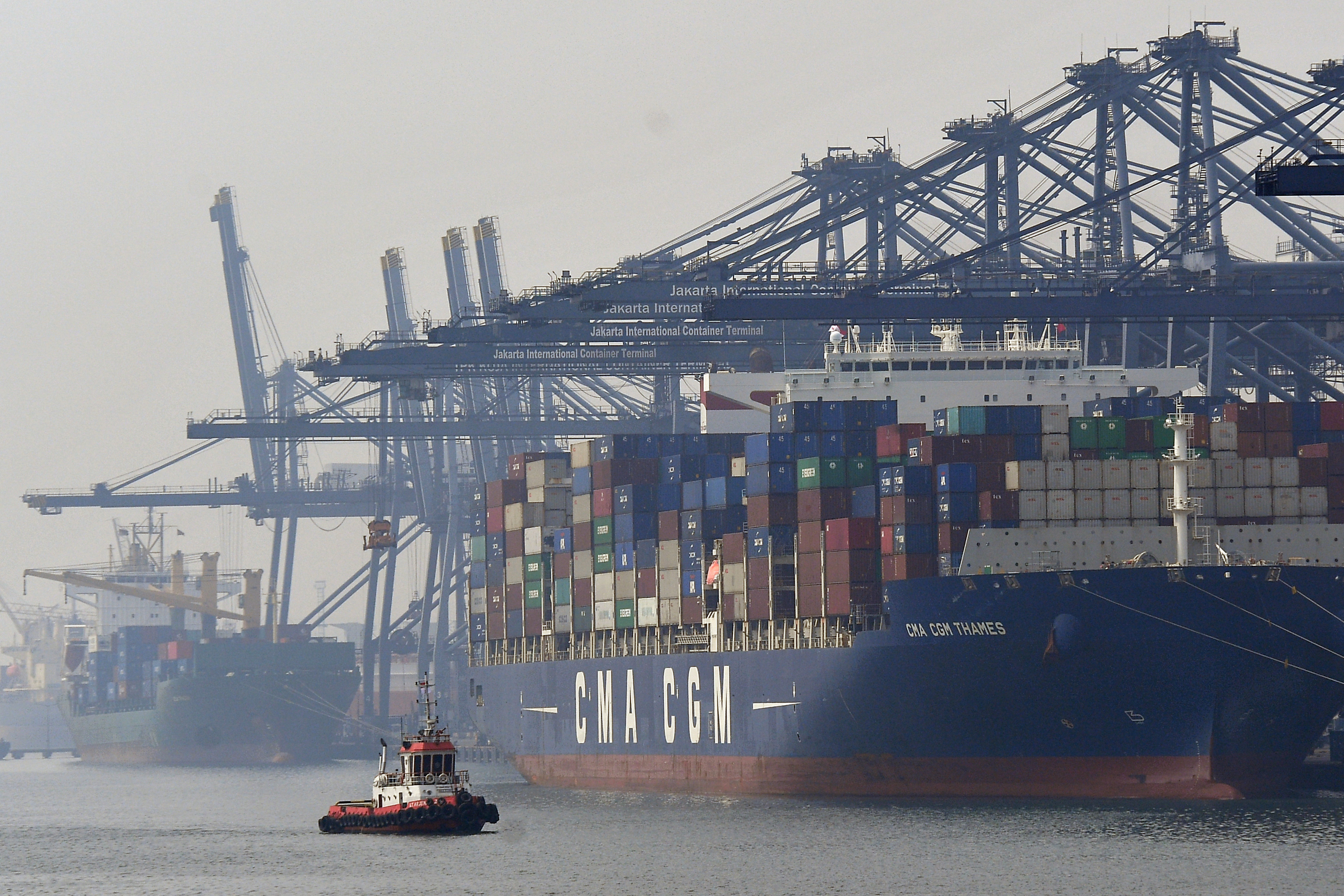  Kapal tunda melintas di dekat kapal yang melakukan bongkar muat peti kemas di Pelabuhan Tanjung Priok, Jakarta.