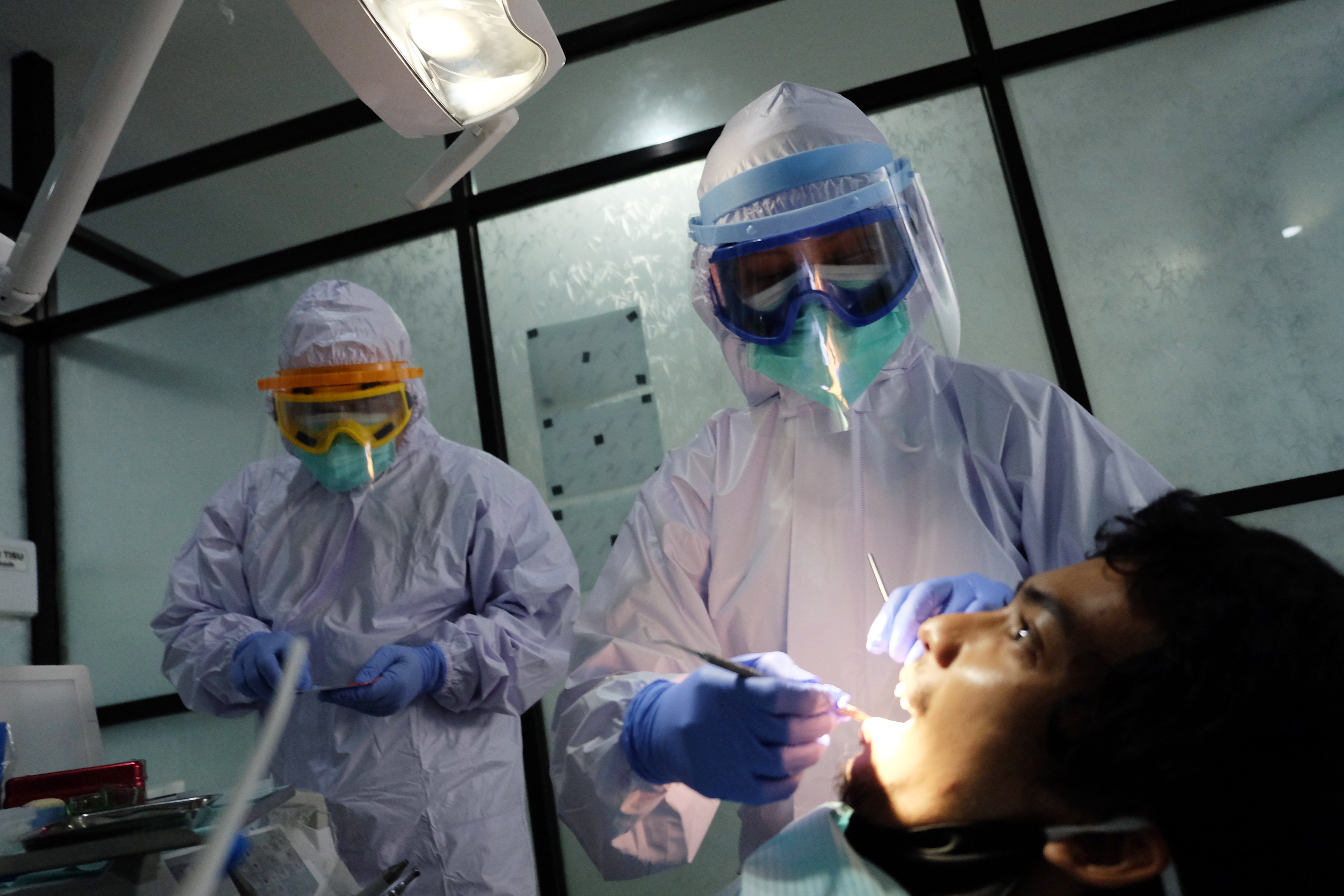 Dokter memakai alat pelindung diri (APD) level III (tiga) saat memeriksa kesehatan gigi pasien.