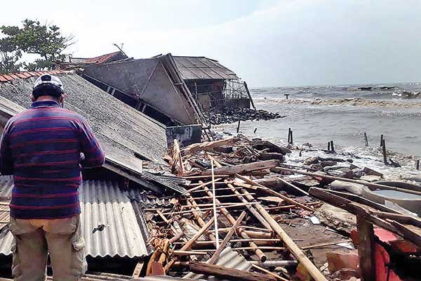 Seorang warga berada di antara rumah yang hancur diterjang gelombang tinggi dan rob di Desa Cemarajaya, Karawang, Jawa Barat, kemarin.