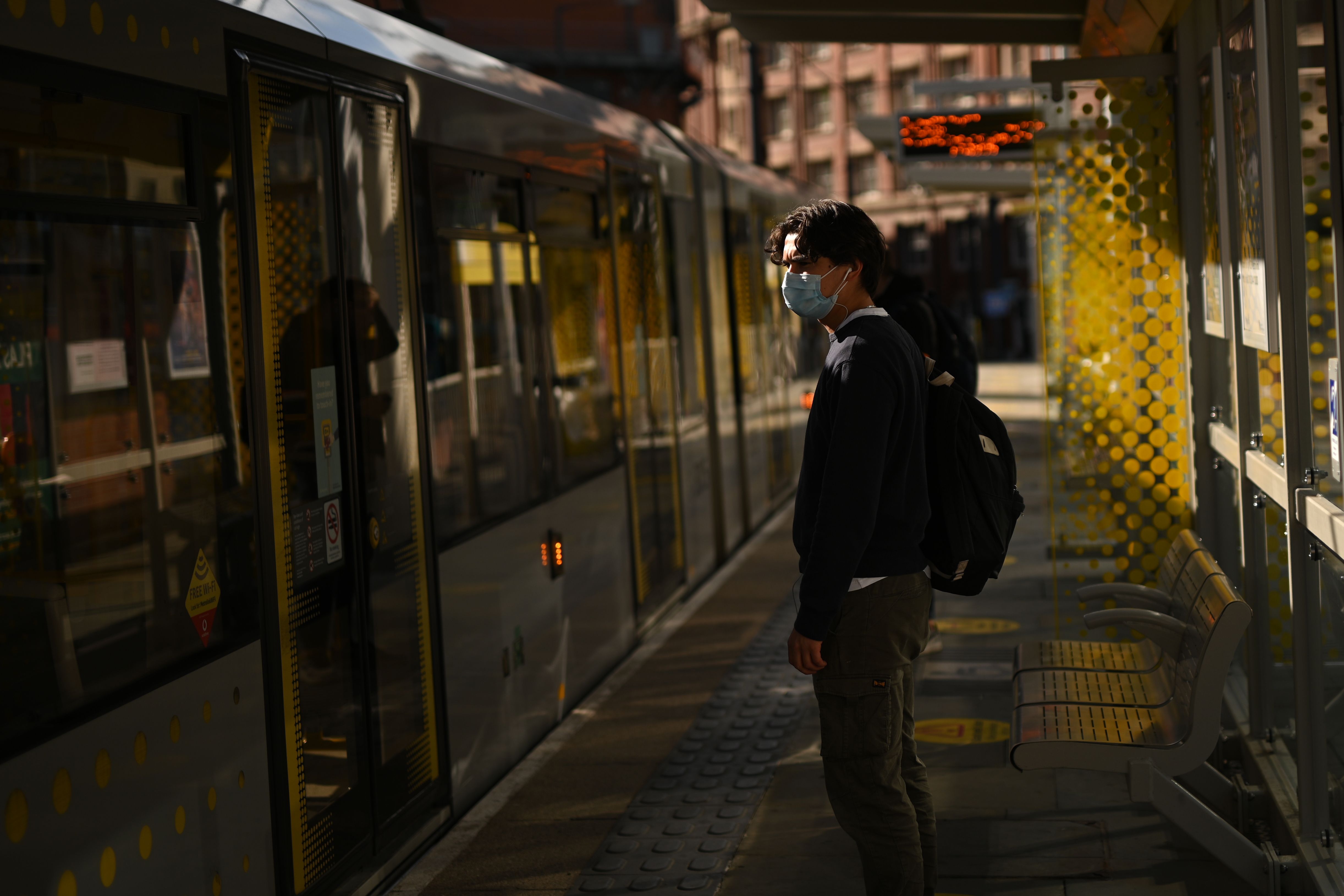 Seorang pria yang mengenakan masker pelindung bersiap untuk naik trem di pusat Manchester, Inggris, Jumat (5/6).