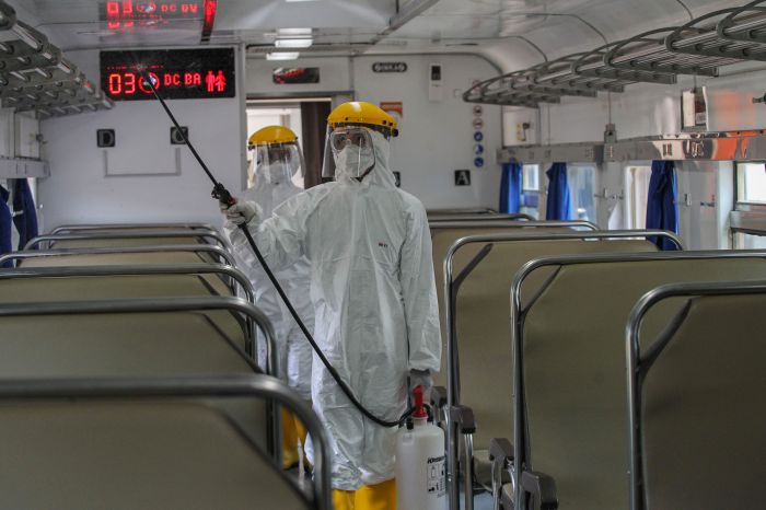 Petugas menyemprotkan cairan disinfektan dalam gerbong kereta api jarak jauh yang sedang dalam proses pembersihan di Stasiun Pasar Senen. 