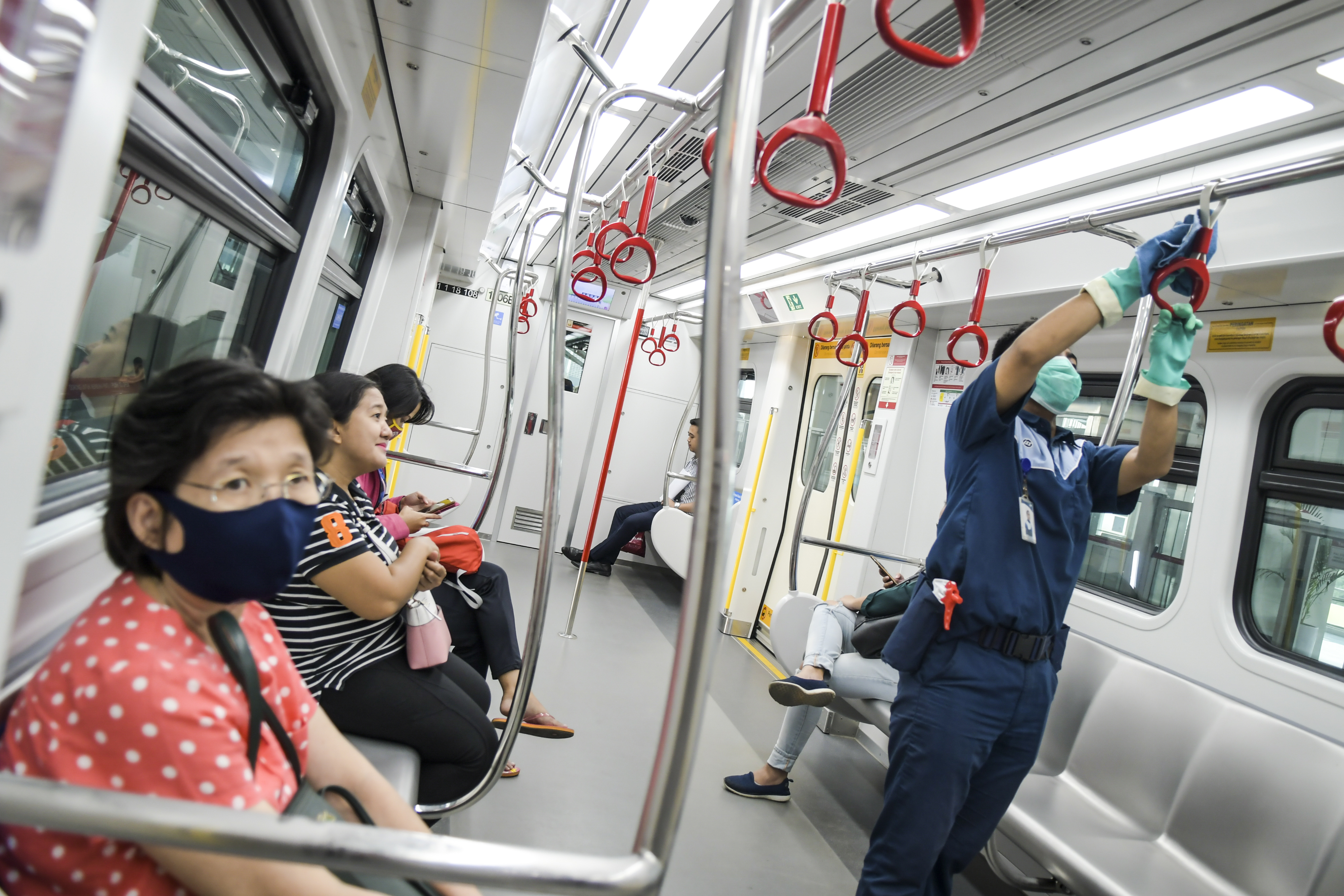Petugas kebersihan membersihkan pegangan tangan gerbong LRT di Stasiun LRT Velodrome, Jakarta