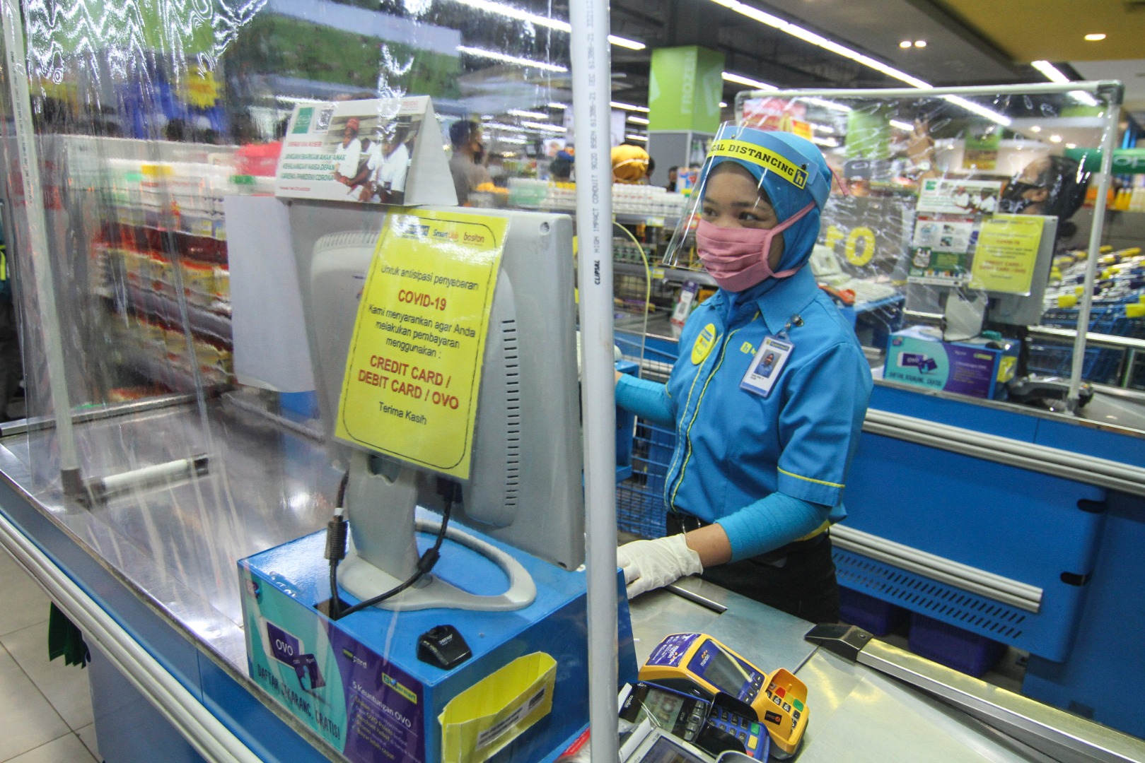 Petugas kasir menggunakan pelindung wajah dan tirai plastik saat melayani pembeli di Mal Depok Town Square, Depok, Kamis (14/6/2020)