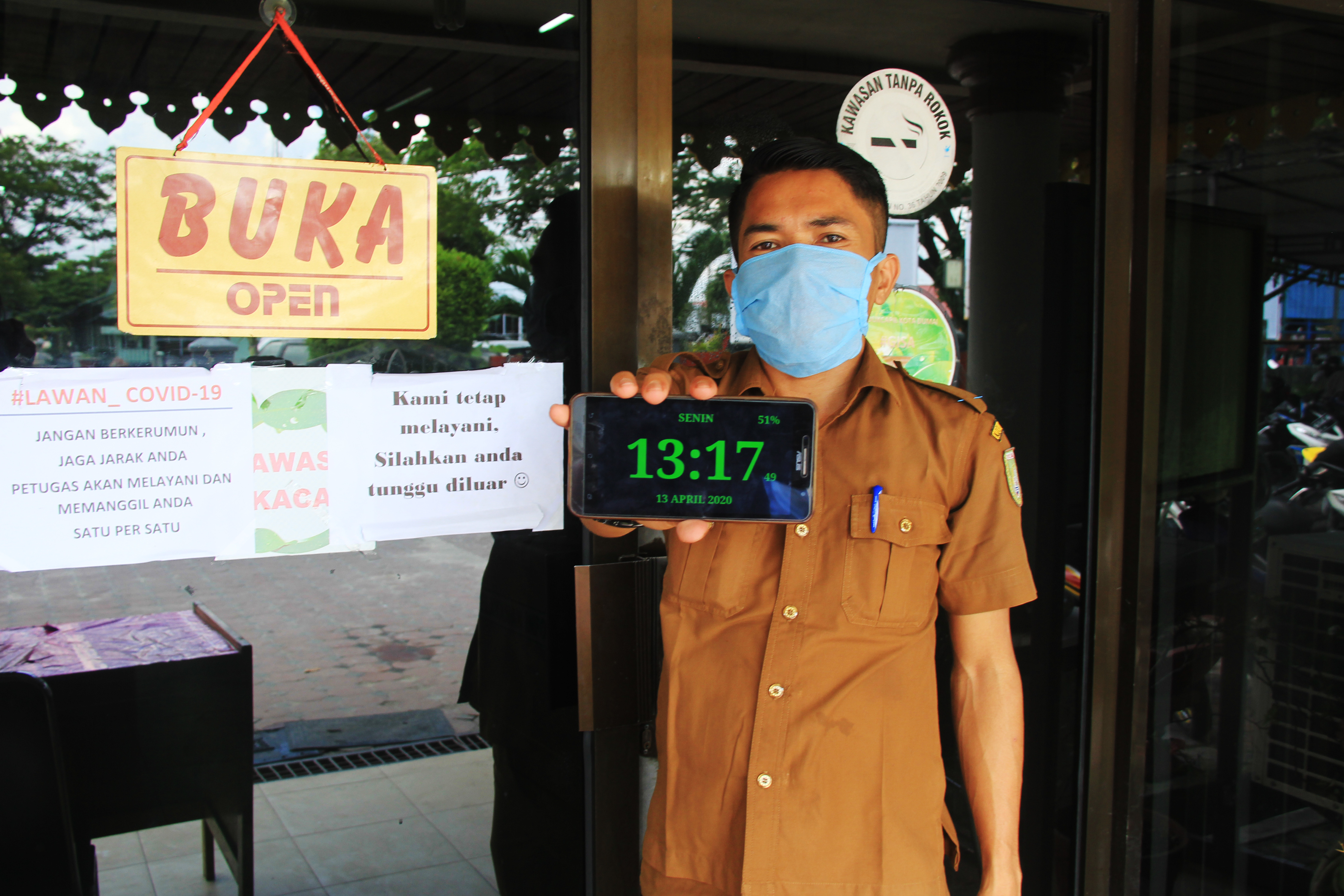 Pegawai Dinas Kependudukan menunjukan waktu pelayanan pada masa darurat kesehatan akibat pandemi COVID-19.