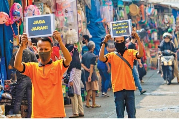 Petugas pengelola pasar melakukan kampanye penggunaan masker dan jaga jarak di Pasar Jatinegara, Jakarta, kemarin.
