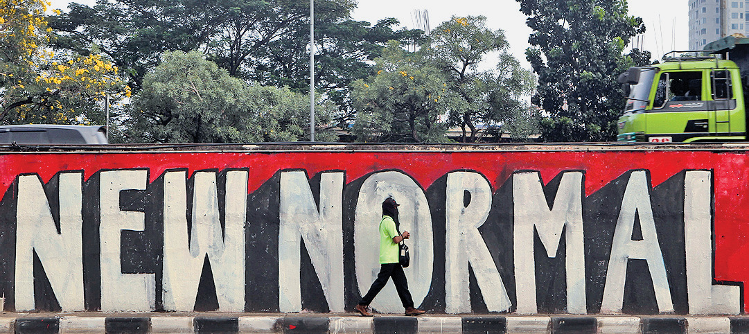 Warga melintas di depan mural bertuliskan ‘New Normal’ di Jalan Tb Simatupang, Jakarta, Sabtu (6/6/2020).