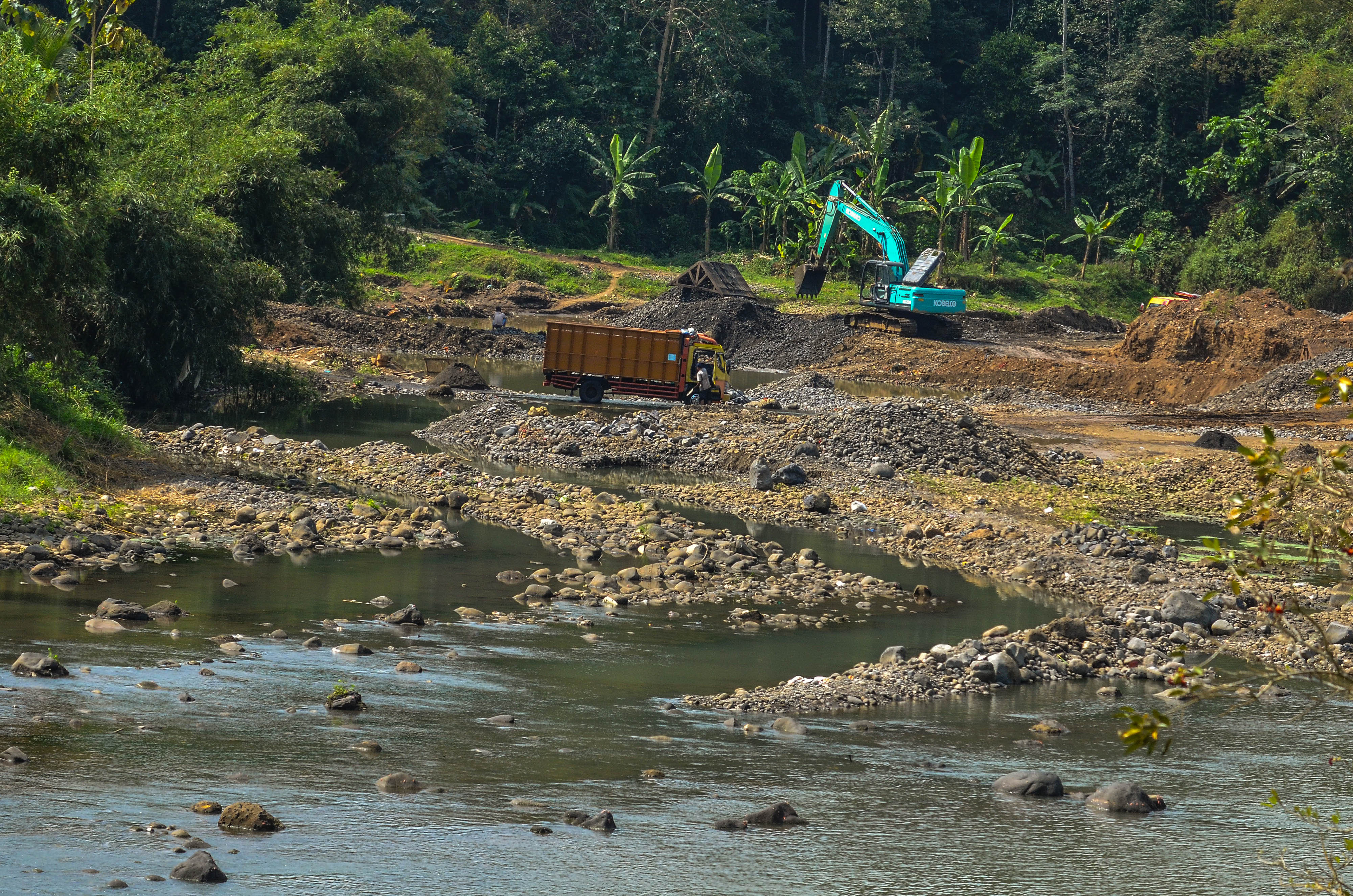 Ilustrasi Pekerja memasukkan pasir ke bak truk dengan alat berat di aliran Sungai Ciwulan, Jatiwaras, Tasikmalaya
