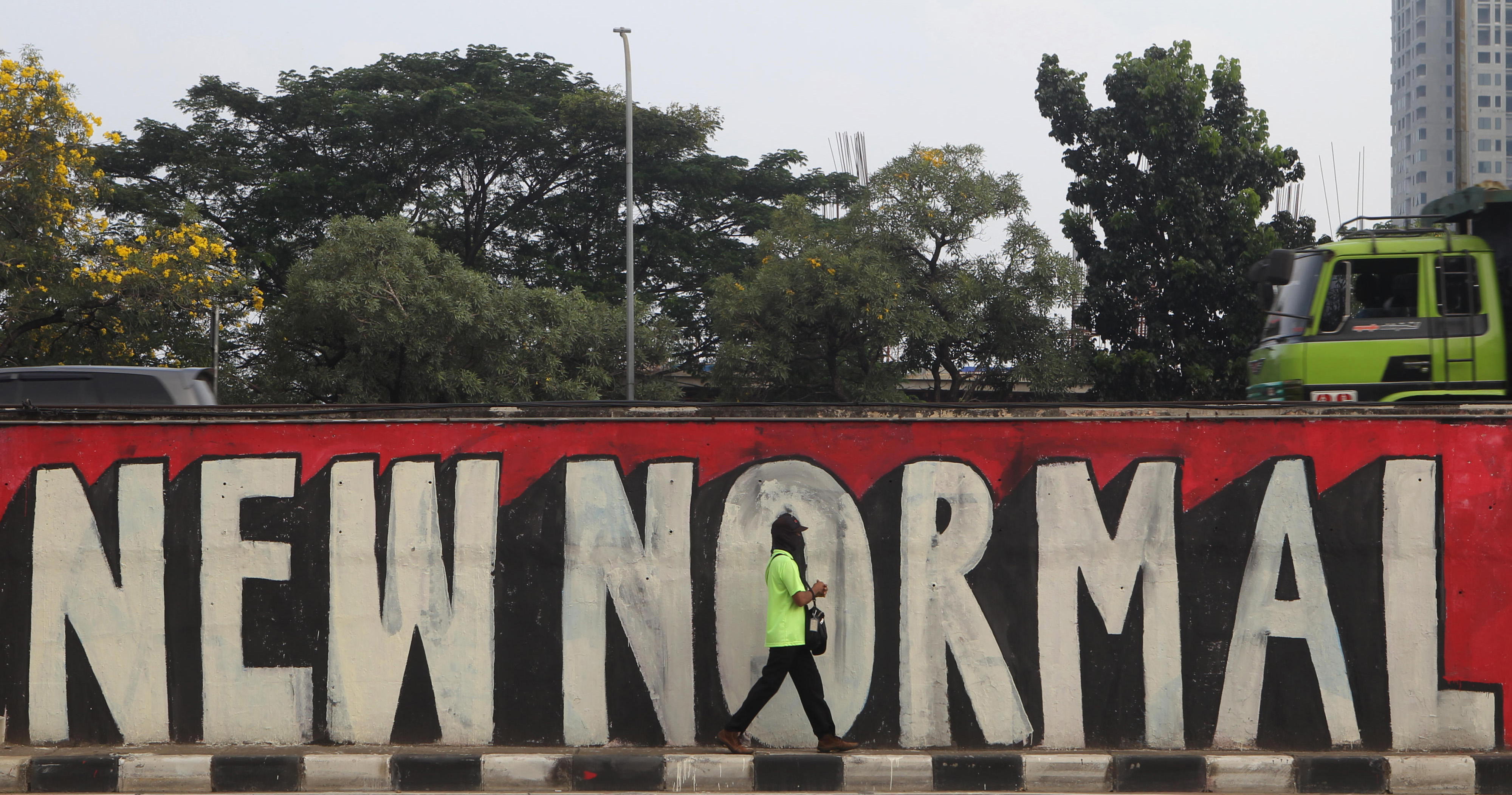 Warga melintas di depan mural bertuliskan ‘New Normal’
