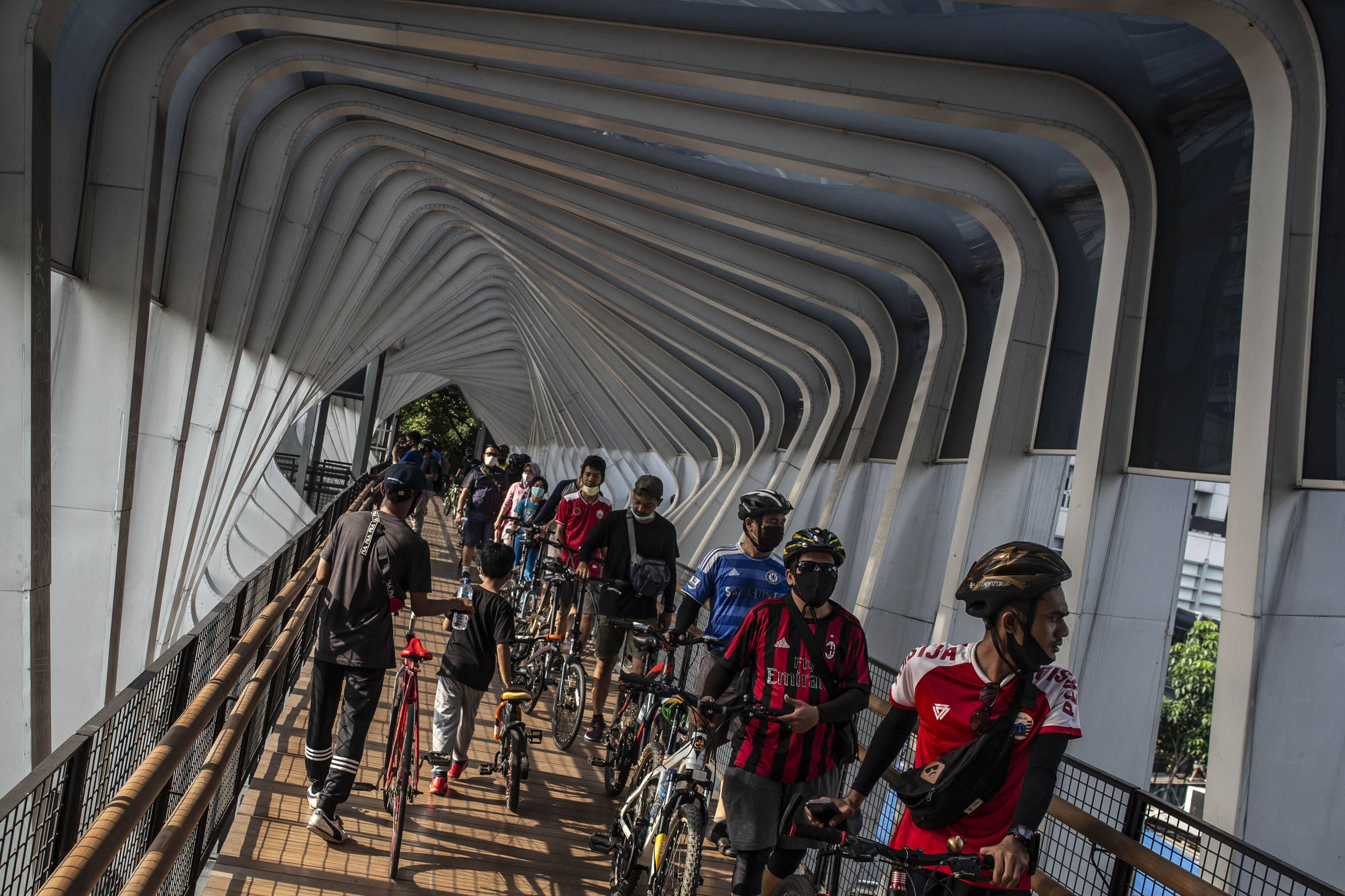 Warga mendorong sepeda saat melintasi JPO di kawasan Sudirman, Jakarta.