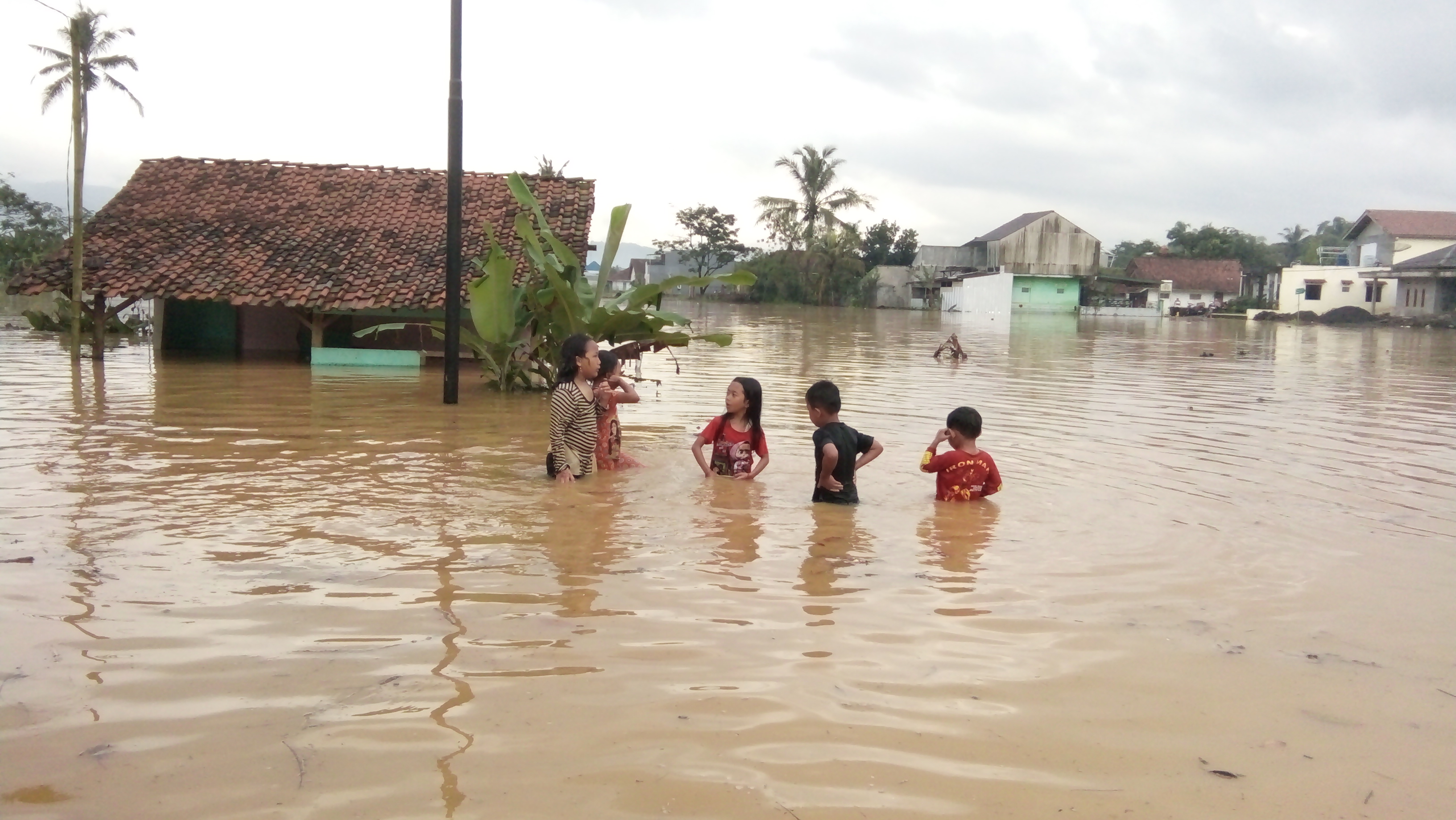 Anak-anak Desa Tanjungsari, Kecamatan Sukaresik, Kabupaten Tasikmalaya bermain di tengah banjir menggenangi 500 rumah di wilayah itu.