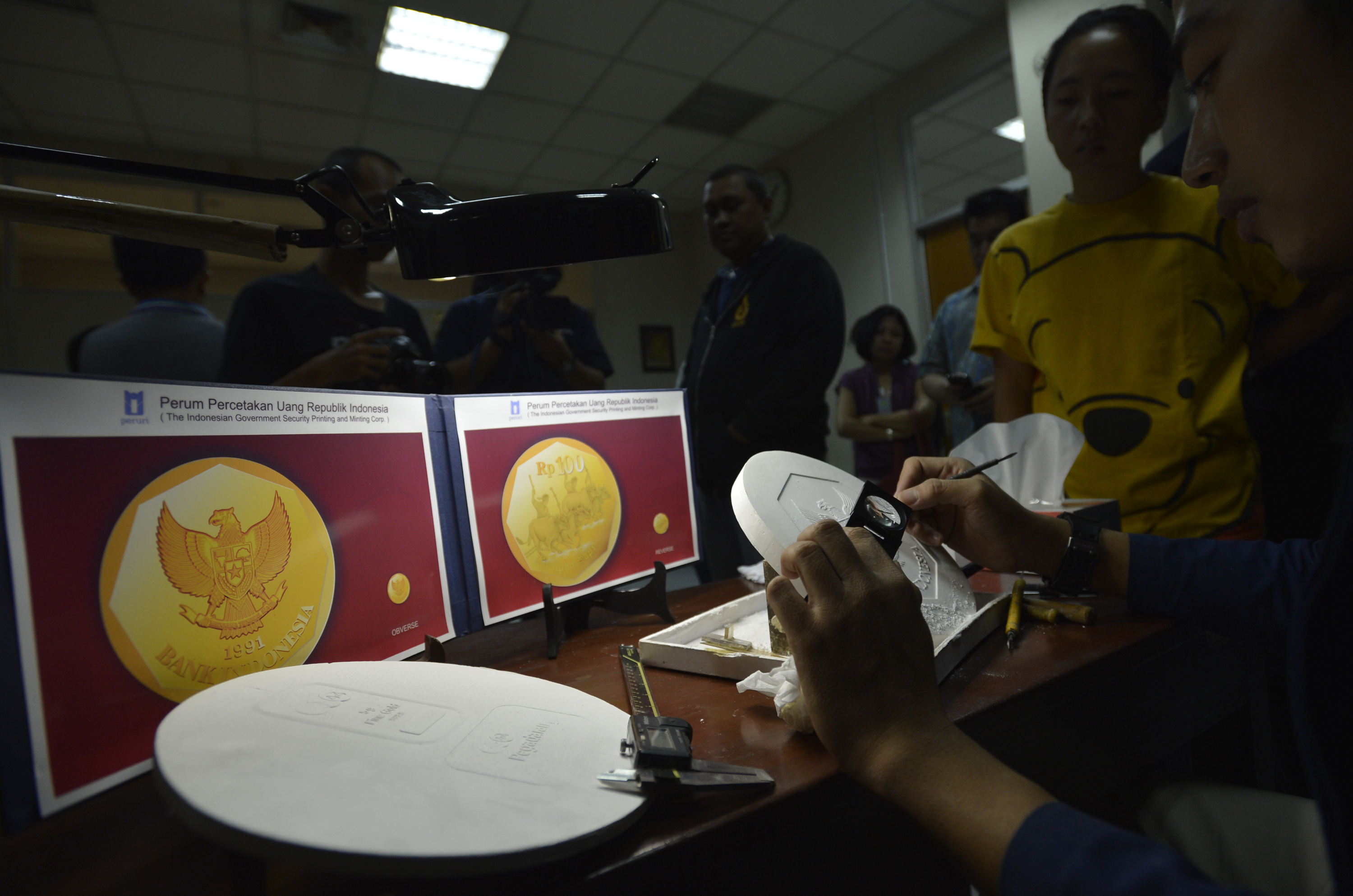 Karyawan Peruri memperegakan cara mendesain uang di plat cetak mata uang logam