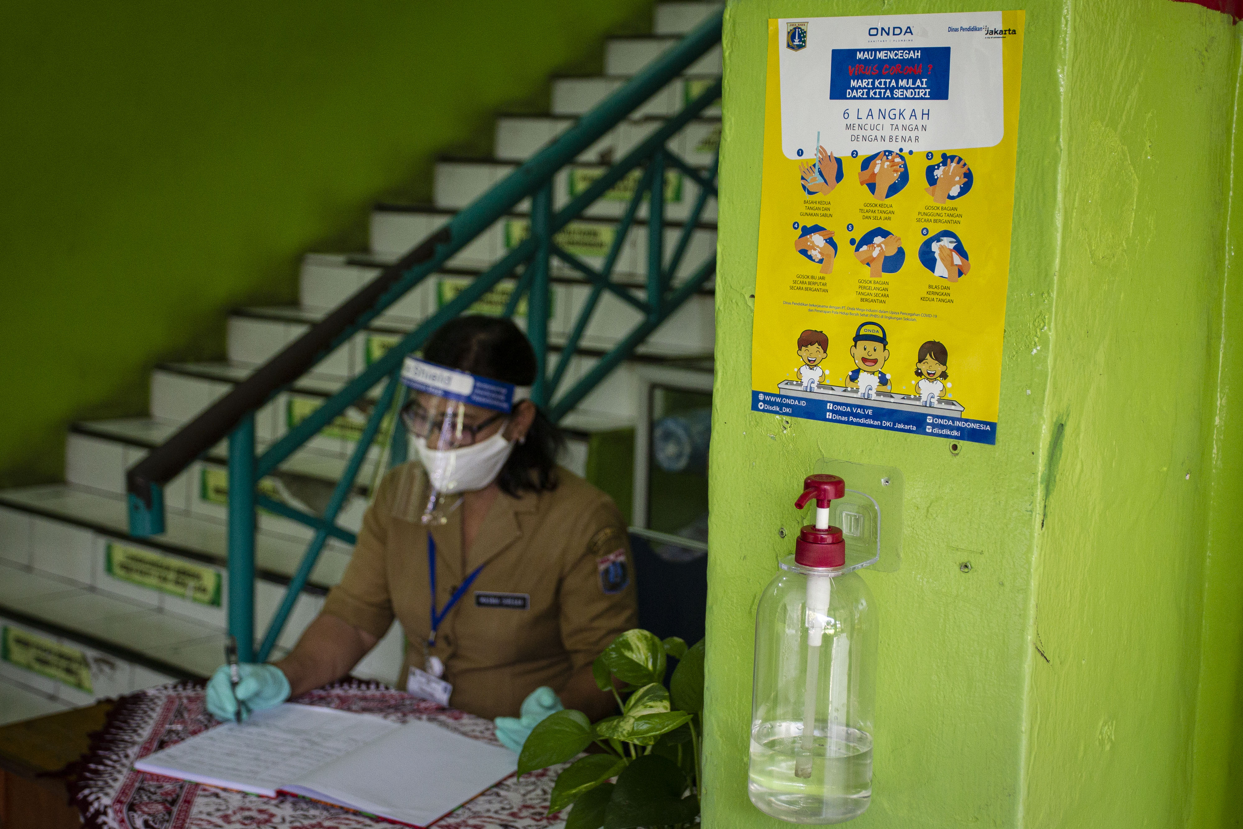 Petugas mengenakan masker dan pelindung wajah saat beraktivitas di sekolah