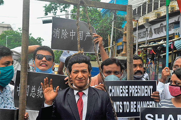 Seorang pengunjuk rasa berpakaian seperti Presiden Tiongkok, Xi Jinping, berdiri di bawah tiang gantungan selama demonstrasi anti-Tiongkok 