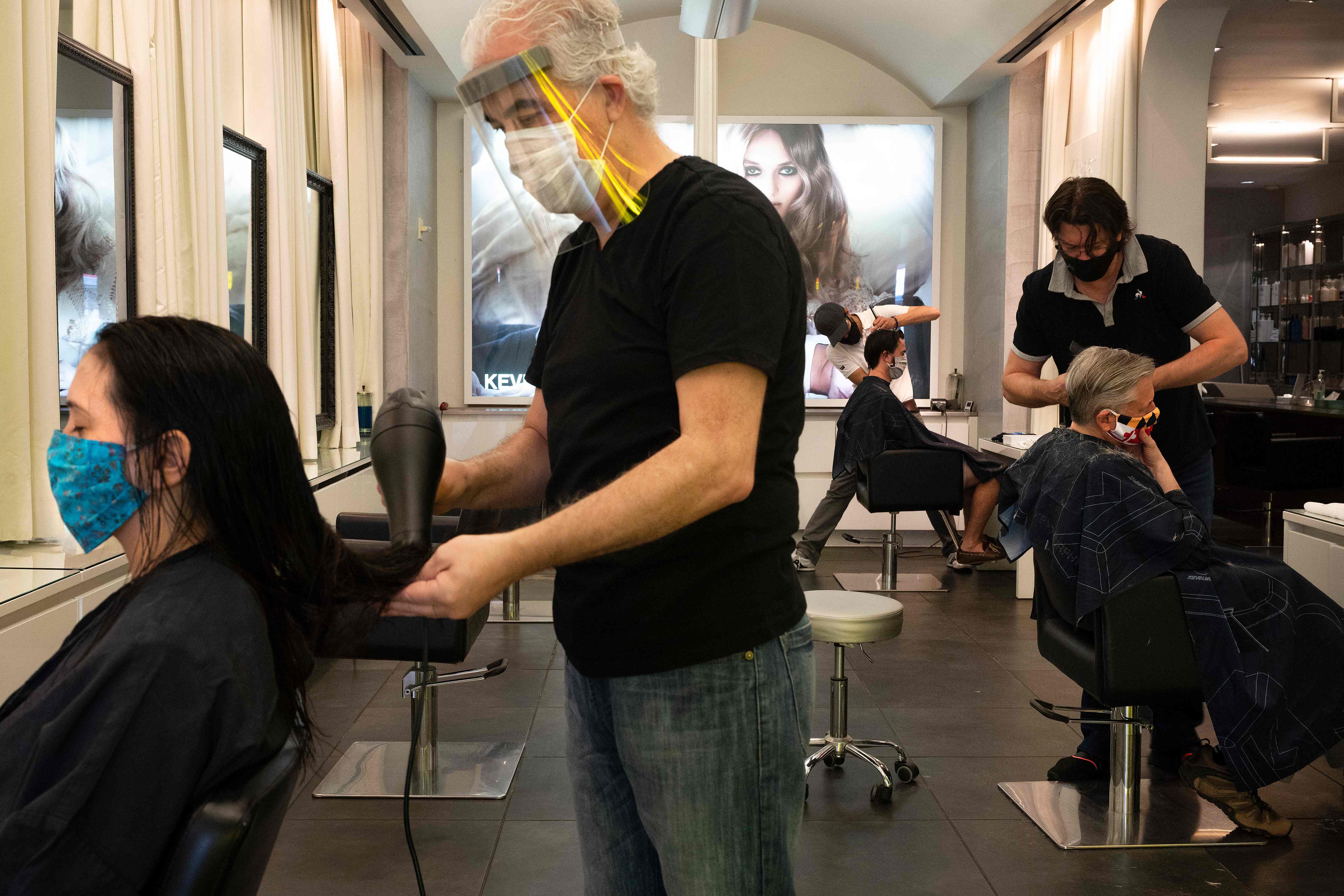 Beberapa penata rambut tengah merapikan rambut pelanggan mereka di sebuah salon.