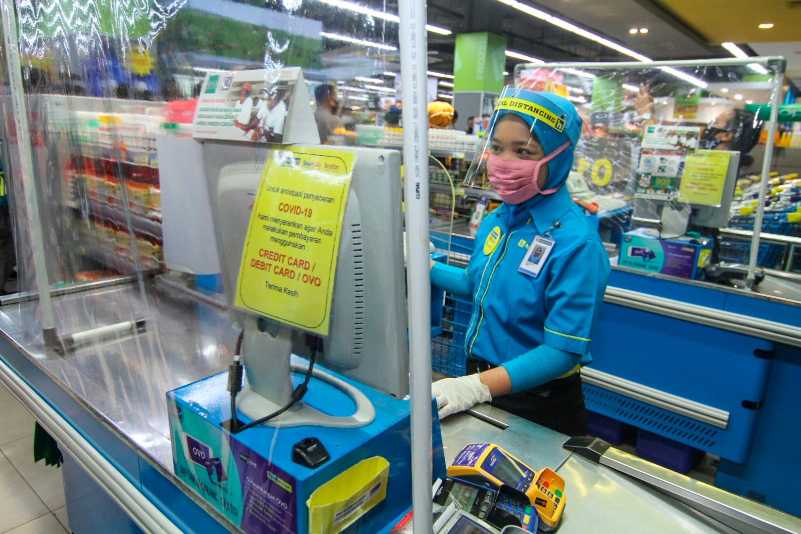  Petugas kasir menggunakan pelindung wajah dan tirai plastik saat melayani pembeli di Mal Depok Town Square, Depok, Jawa Barat, Kamis (4/6)