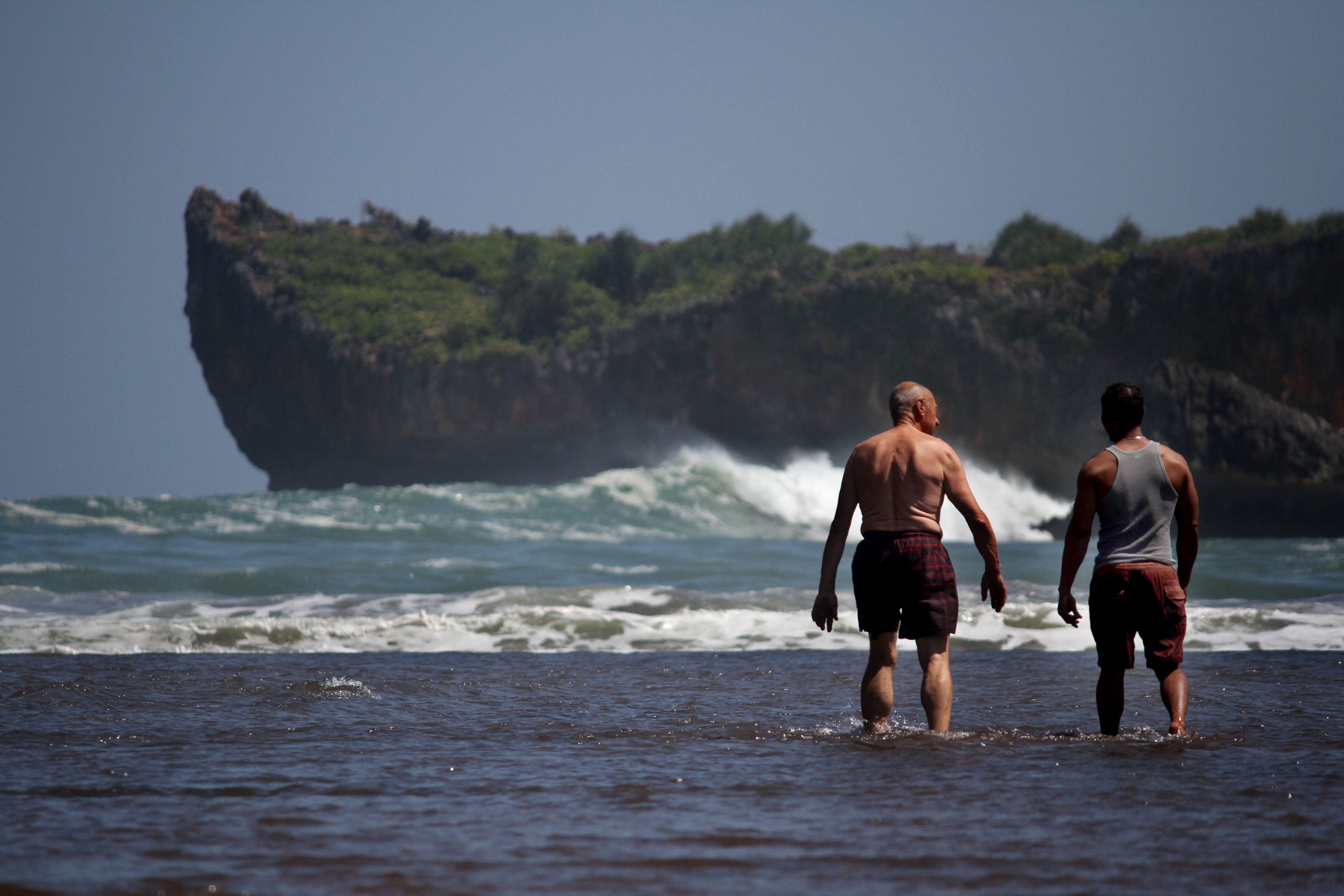 Wisatawan berjalan untuk mandi di laut saat berwisata di Pantai Baron, Gunung Kidul, Daerah Istimewa Yogyakarta,