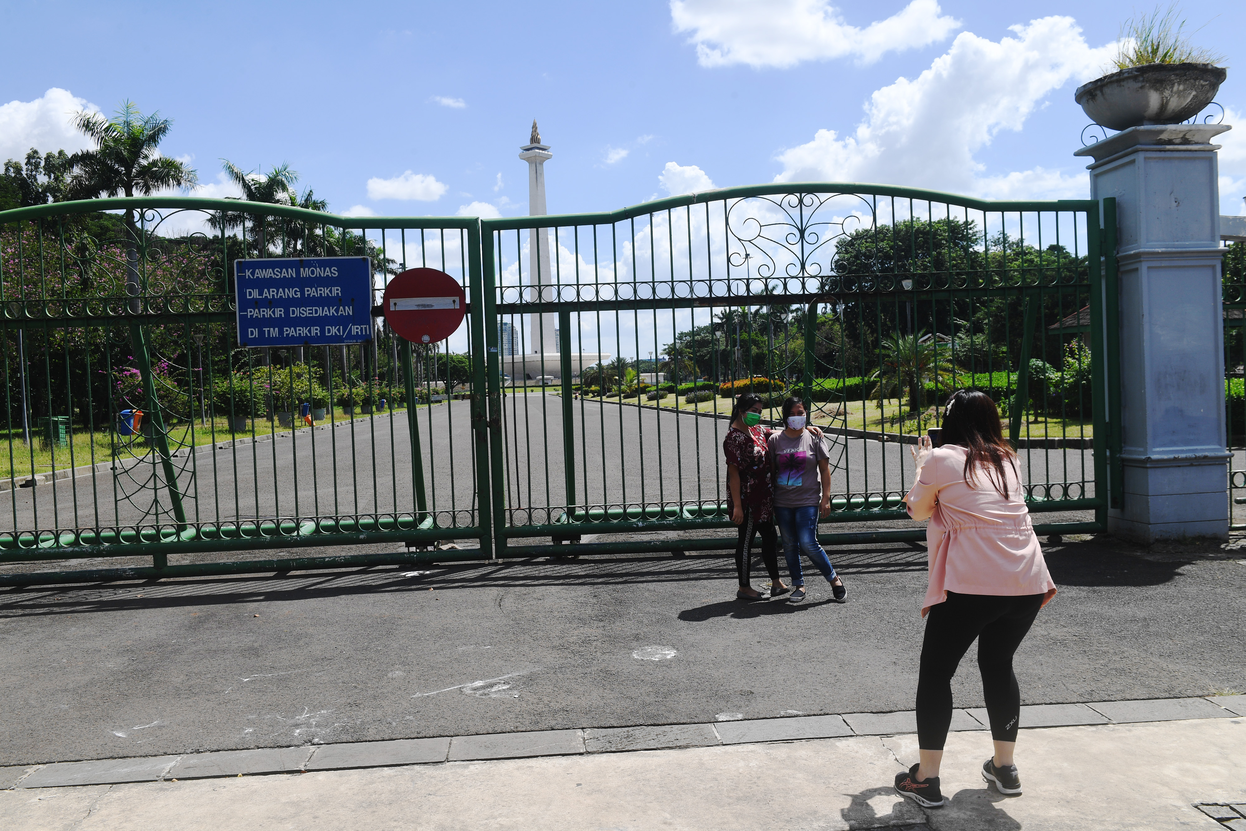 Warga berfoto diluar pagar Monas yang ditutup selama penerapan PSBB di Jakarta