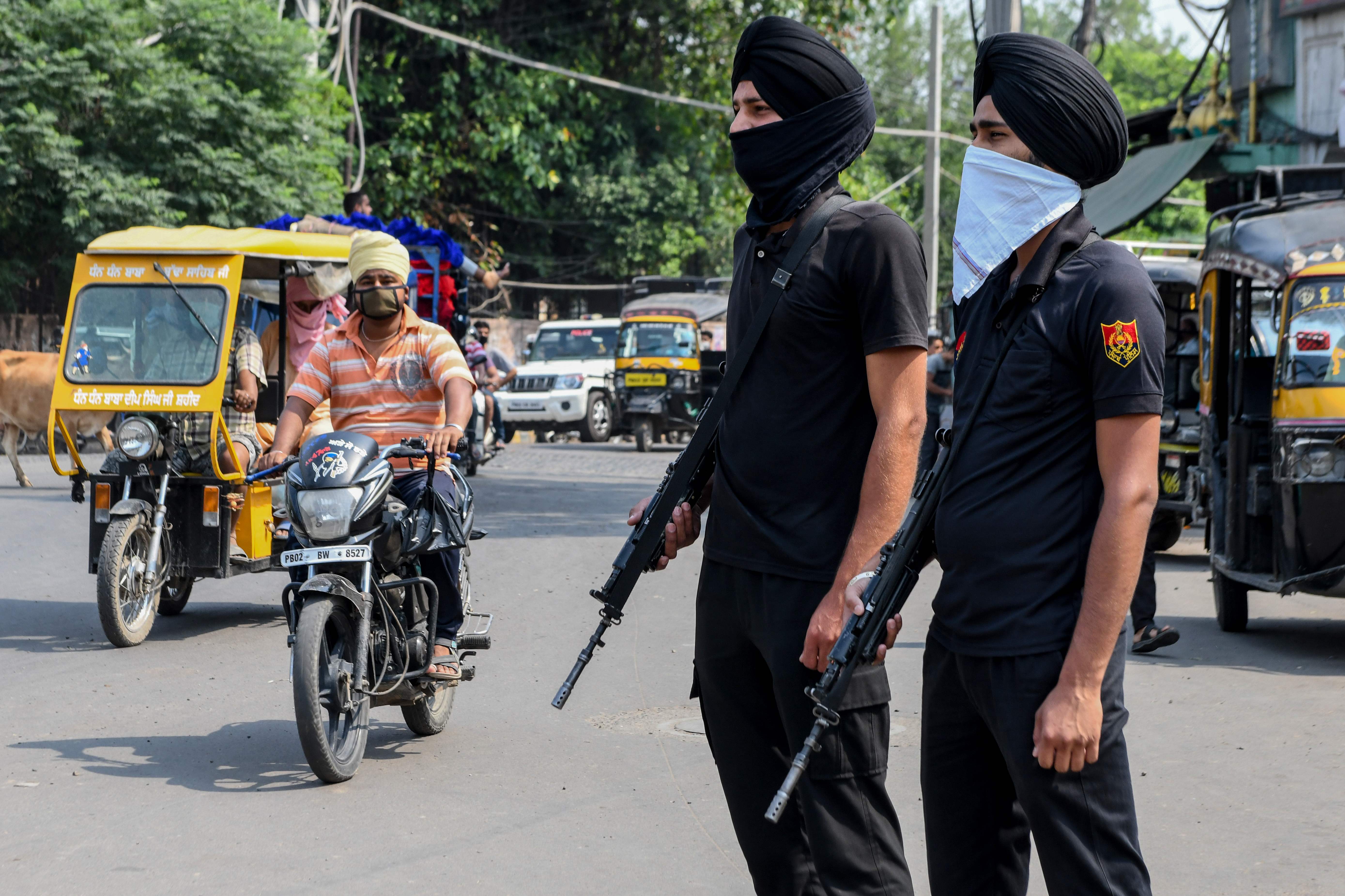 Dengan menggunakan masker kain, polisi India berpatroli di jalanan.