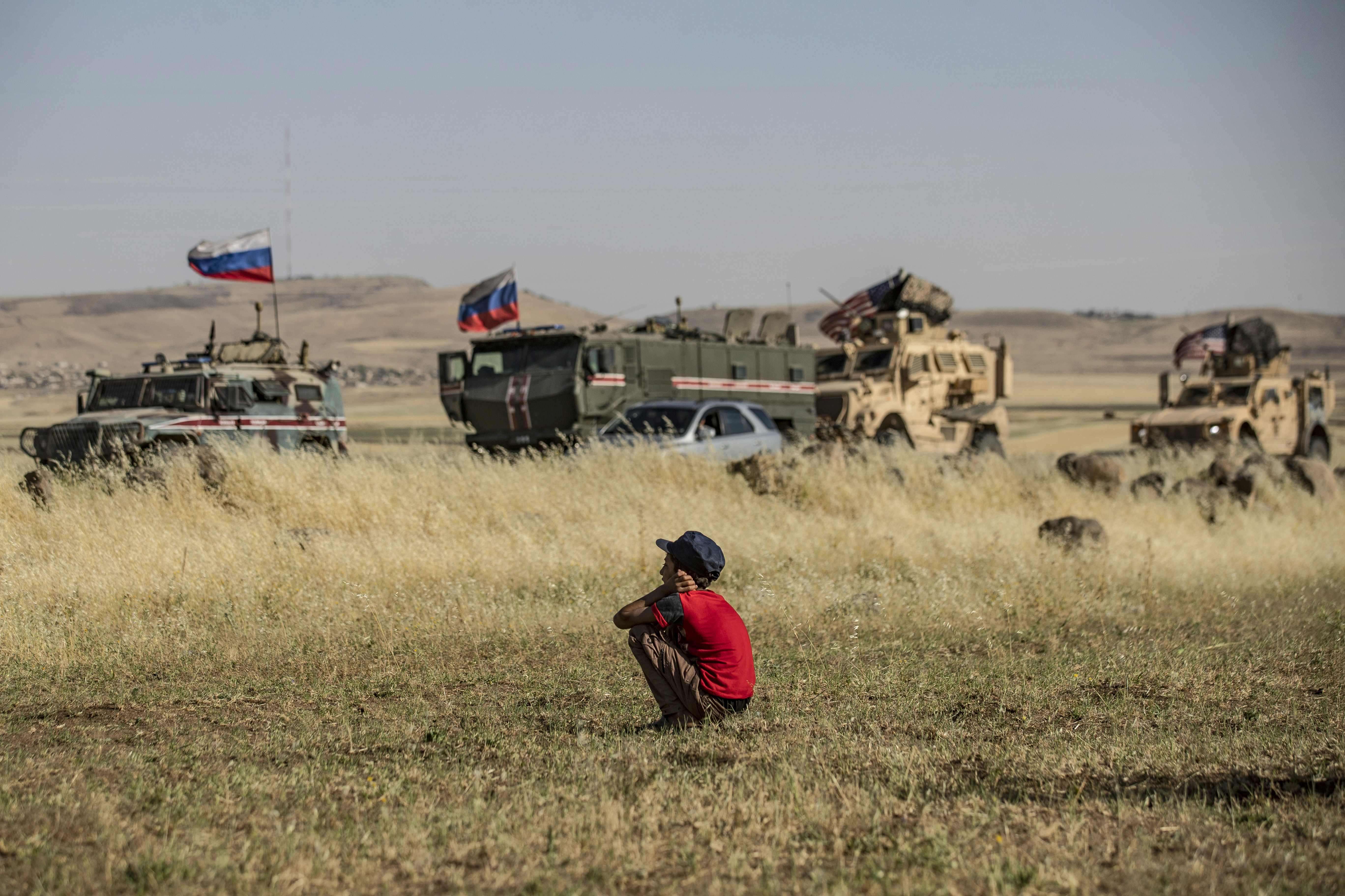 Seorang anak sedang melihat konvoi pasukan Rusia dan Amerika di al-Malikiyah (3/6/2020)