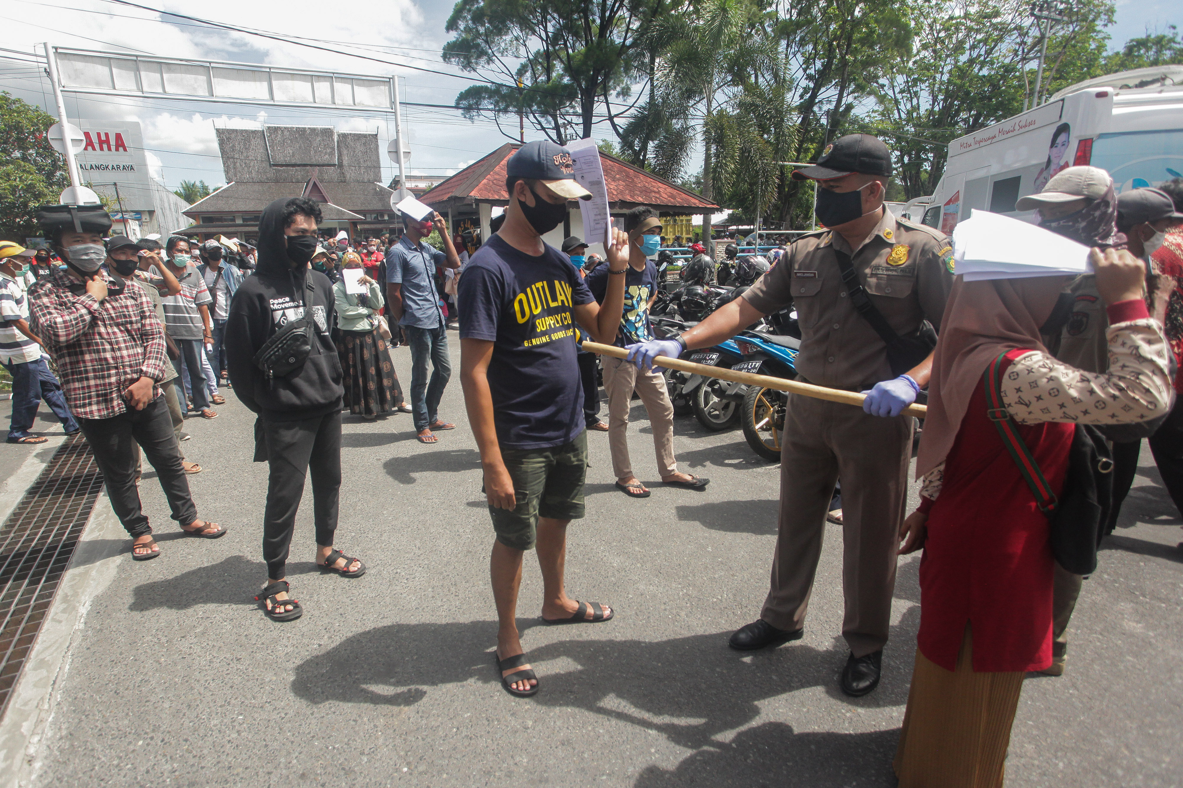 Petugas mengatur jarak fisik warga saat mengantre Bantuan Langsung Tunai (BLT) di Palangkaraya, Kalimantan Tengah, Minggu (31/5).