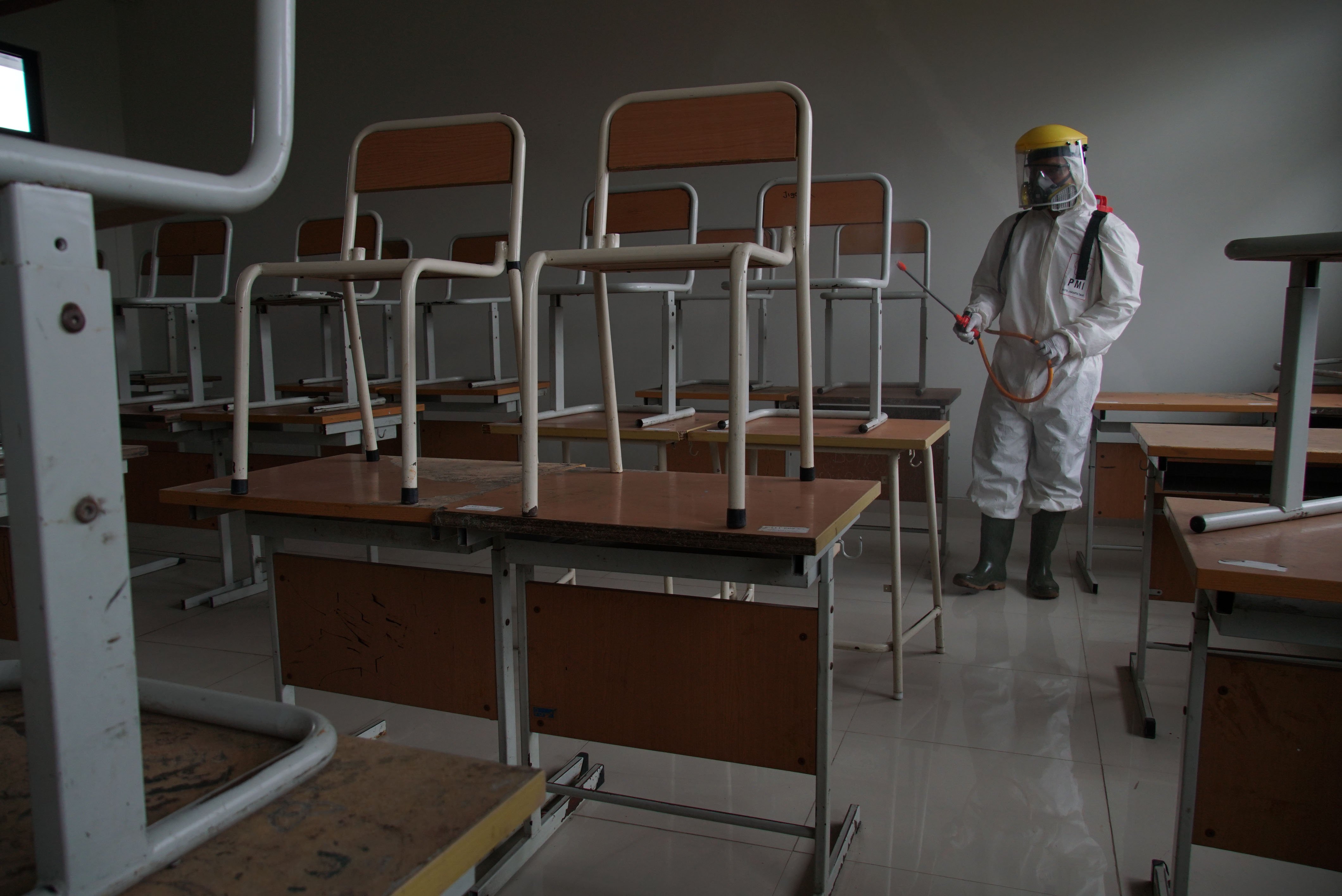 Petugas PMI Kota Jakarta Timur menyemprotkan cairan disinfektan di ruang kelas SMP Negeri 148 Jakarta, Jakarta, Senin (22/6).