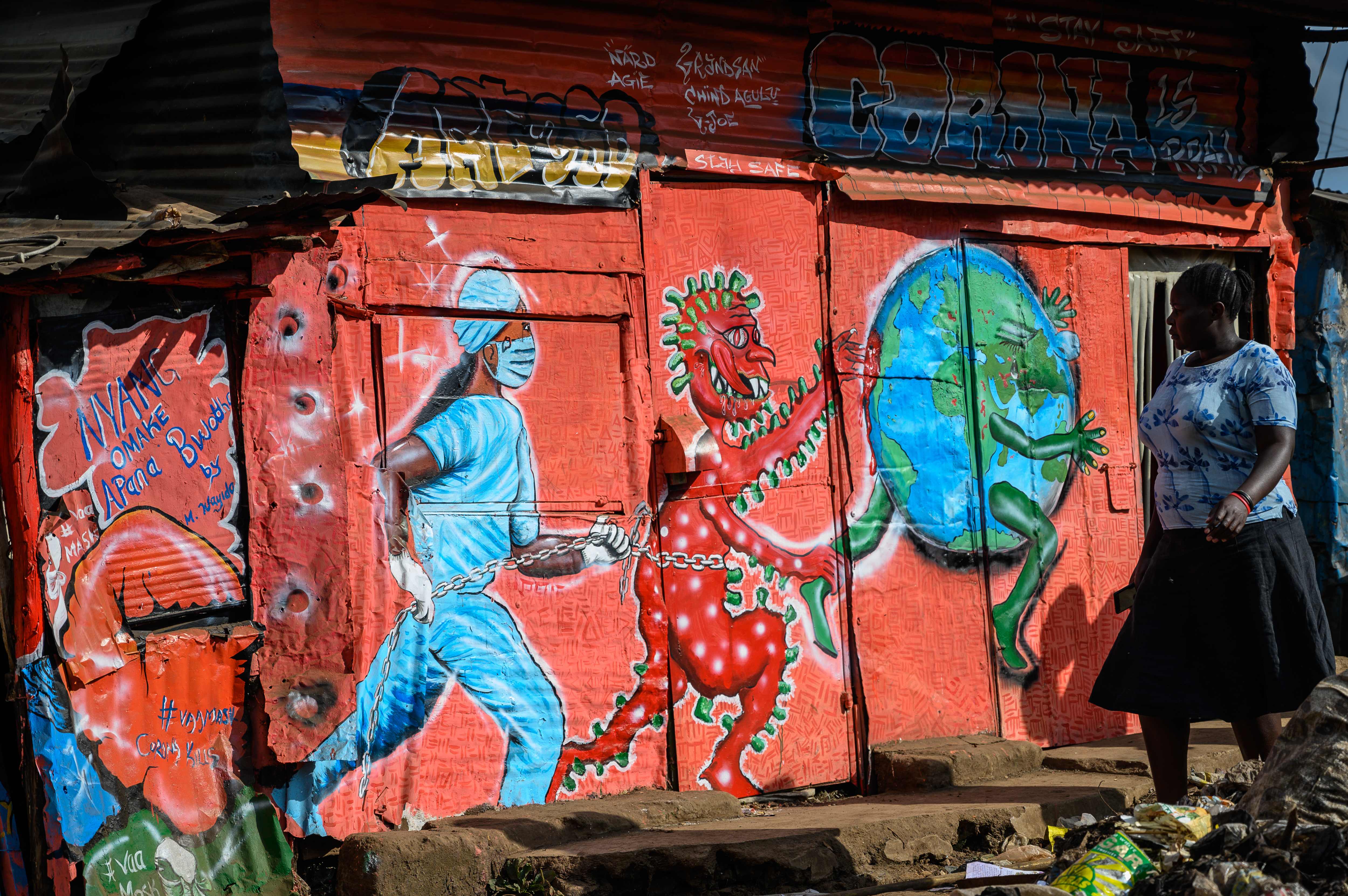Seorang wanita berjalan melewati mural grafiti yang terkait covid-19 yang dilukis kelompok, art360, di Nairobi, Kenya, Selasa (2/6).
