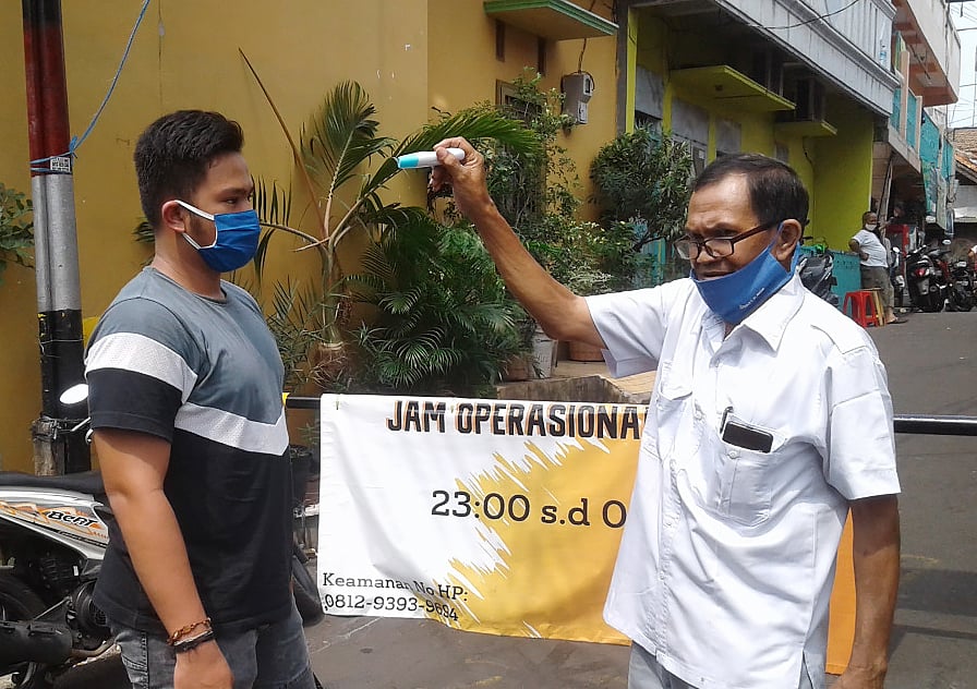 Warga memeriksa suhu tubuh seorang tamu yang akan berkunjung di RW 12, Kelurahan Kebon Melati, Jakarta Pusat