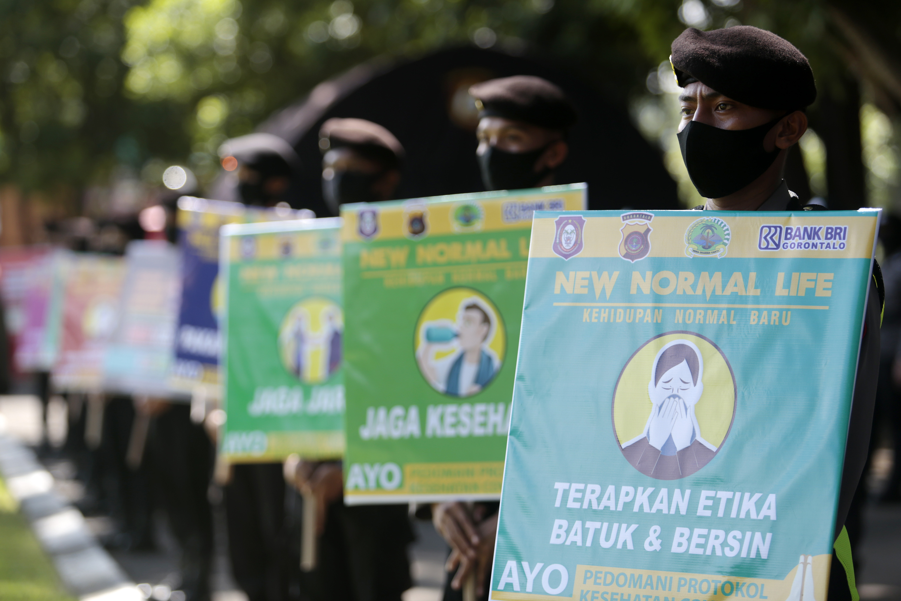 Personel kepolisian di Gorontalo memegang papan imbauan terkait penerapan new normal.