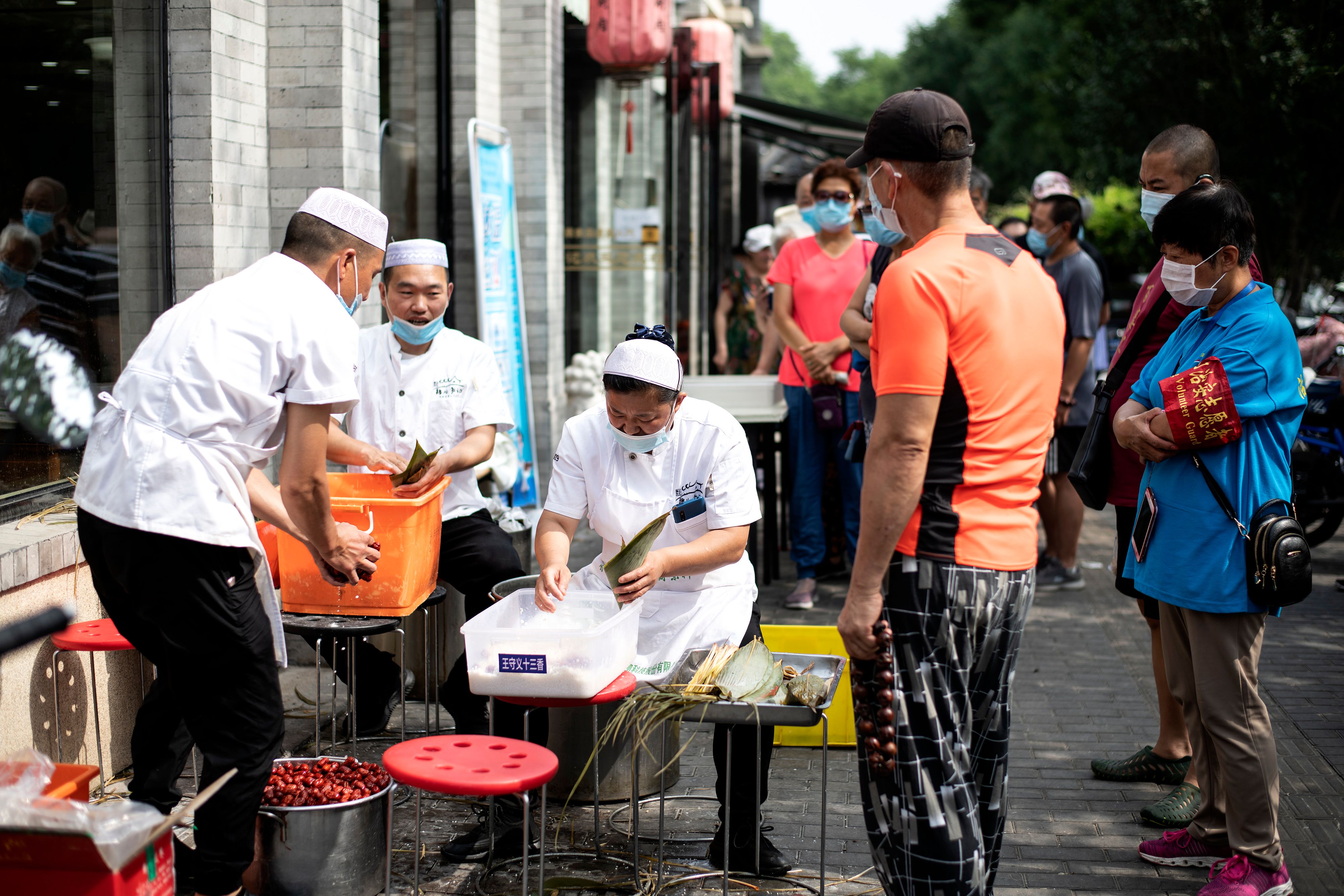 Pekerja yang memakai masker wajah menyiapkan makanan di sepanjang jalan di Beijing, Kamis (25/6).