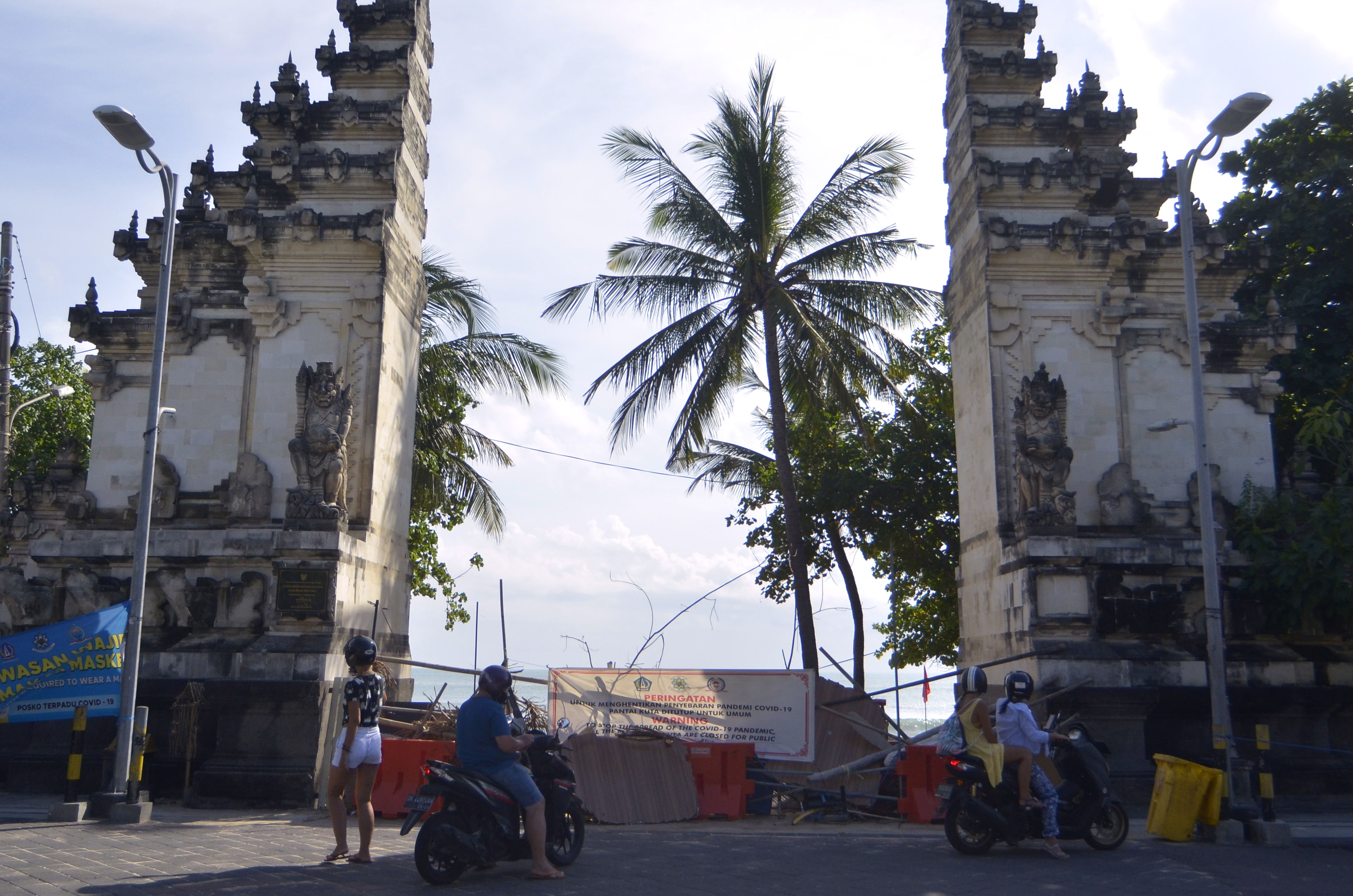 Wisatawan berada di luar kawasan Pantai Kuta yang ditutup sementara di Badung, Bali, Minggu (31/5/2020).