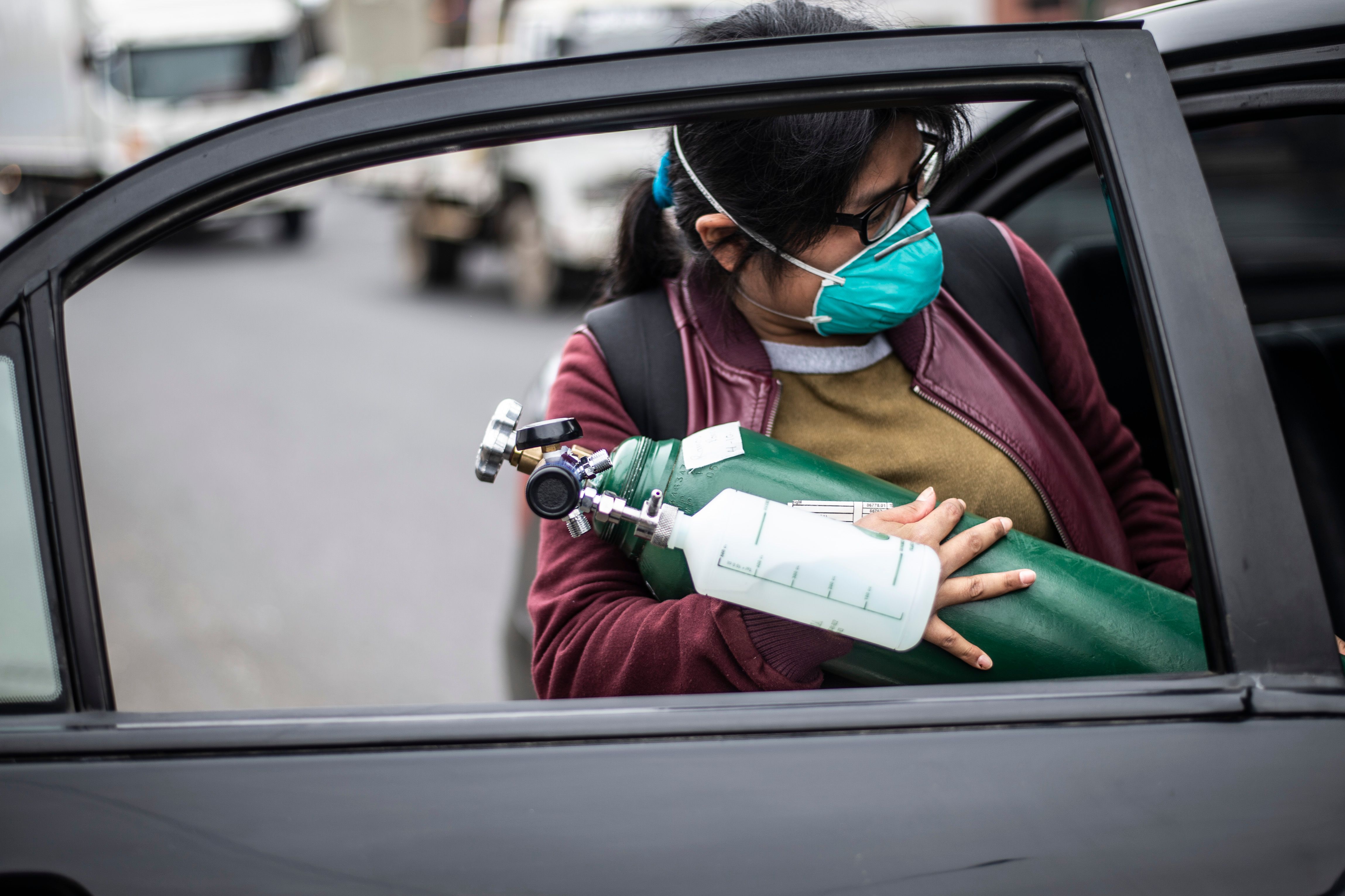 Seorang wanita yang membawa tabung oksigen untuk seorang kerabatnya yang dirawat di RS 2 de Mayo di Lima, Peru, Minggu (3/6).