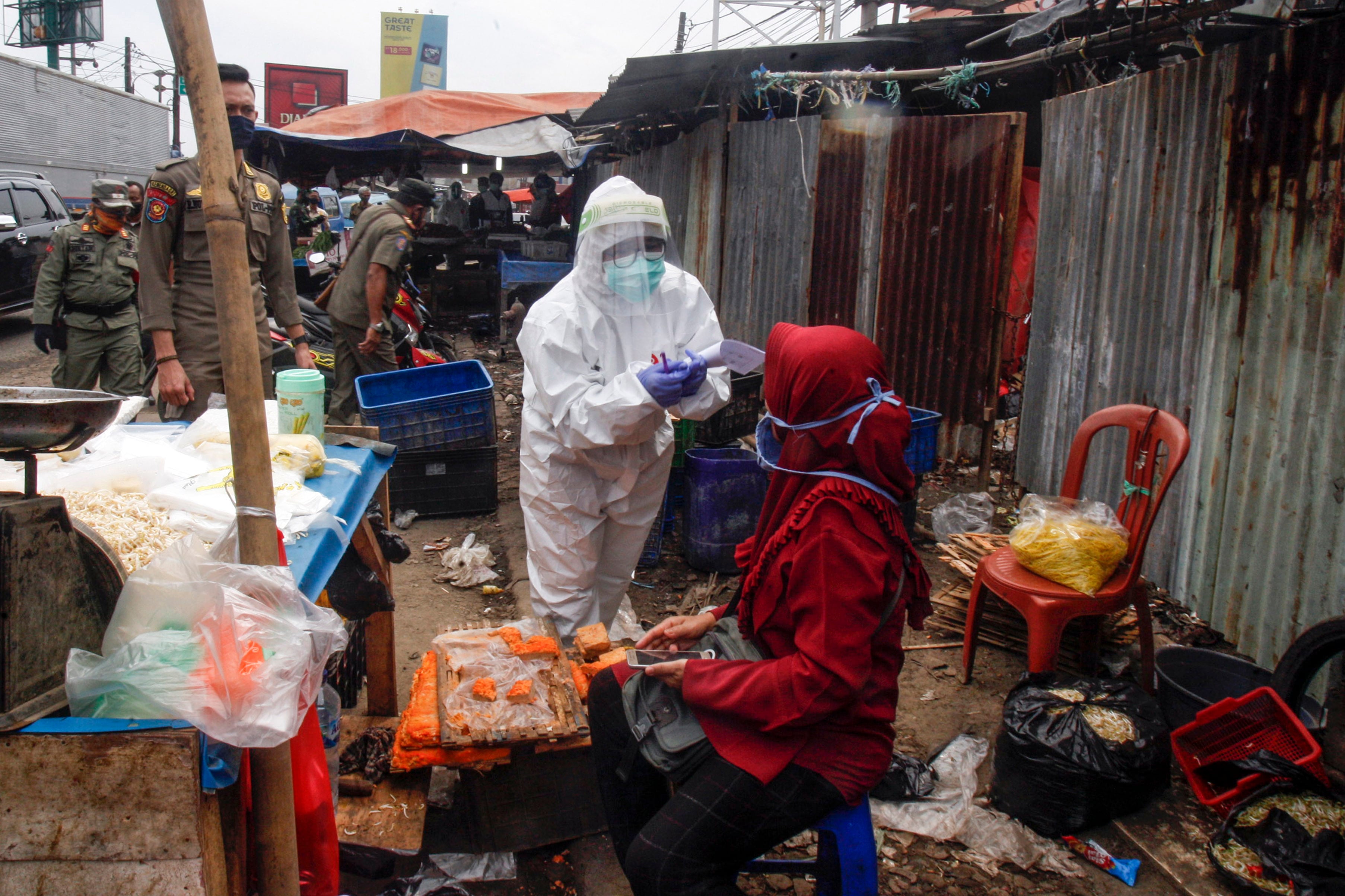  Petugas menggunakan alat pelindung diri (APD) lengkap melakukan tes diagnosa cepat (rapid test) pedagang pasar di Pasar Cileungsi, Bogor.