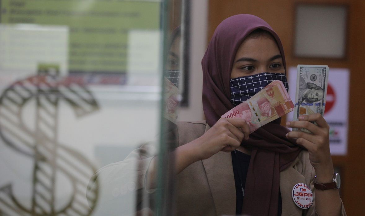 Karyawati menunjukkan mata uang rupiah dan dolar AS di salah satu gerai penukaran mata uang asing di Jakarta, Minggu (7/6/2020). 